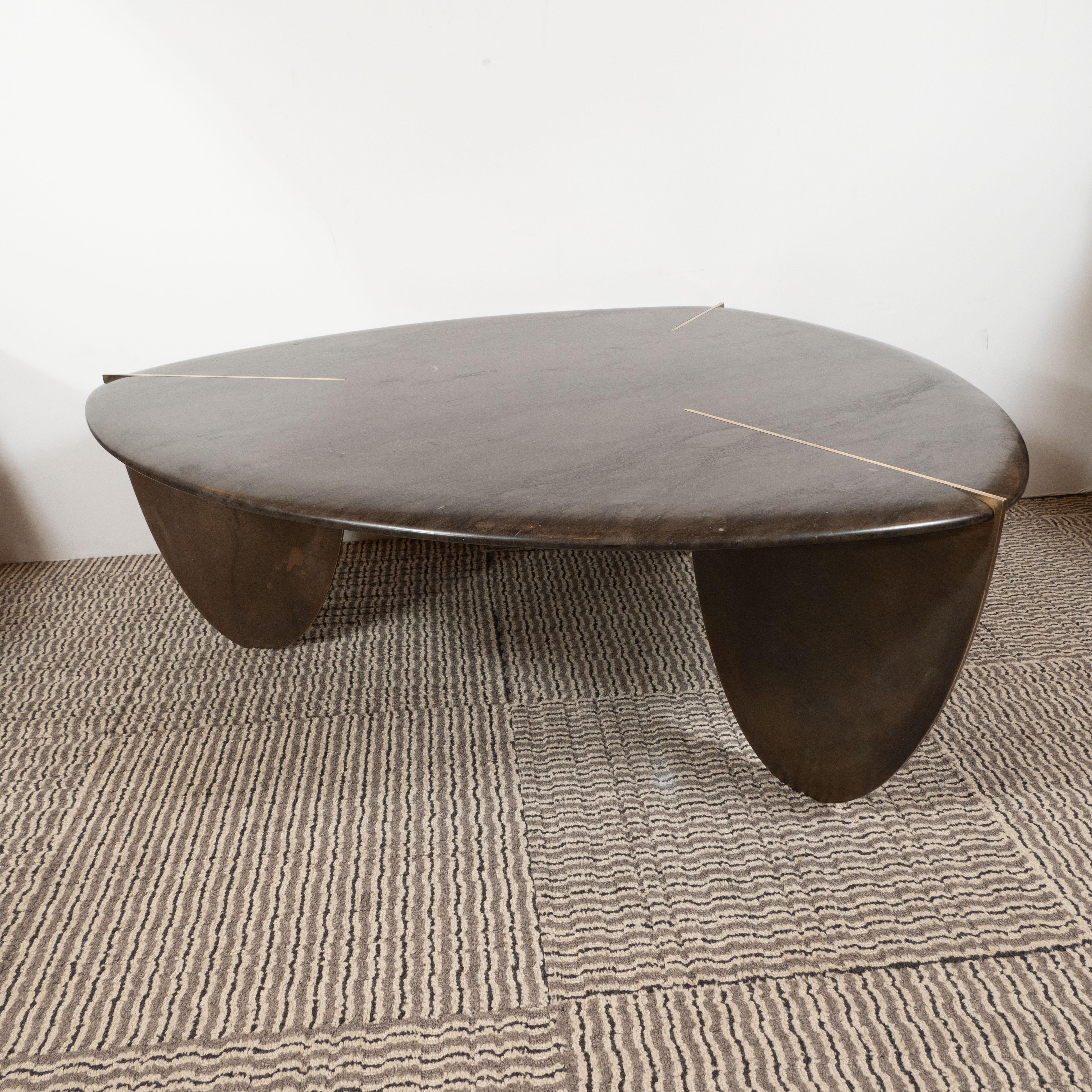 This stunning and refined organic modernist cocktail table was custom designed and fabricated in the United States by hand. It features a shield form in java hued armani marble with bowed sides that comes to three rounded points bisected by