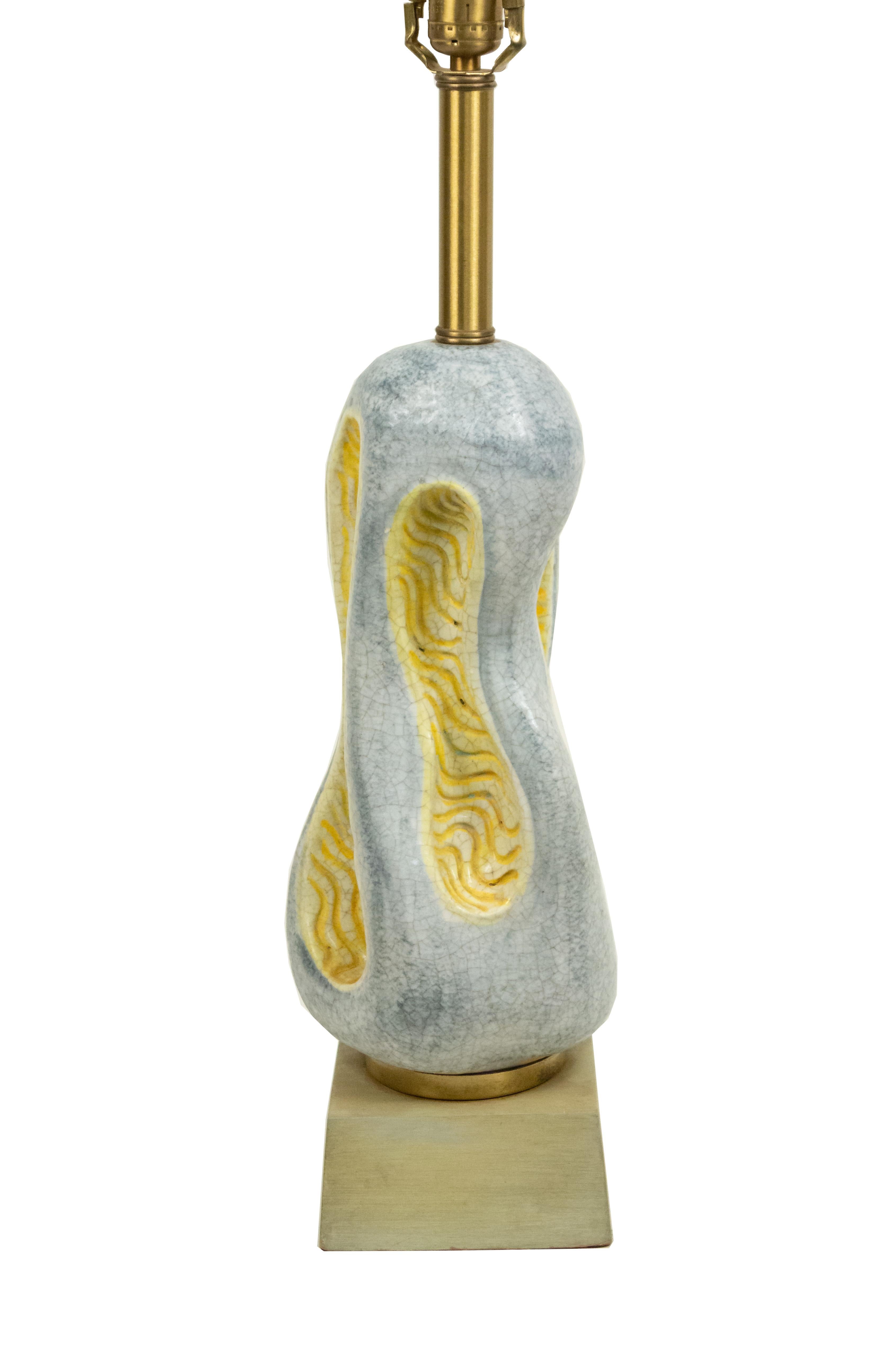 Lampe de table en céramique bleue et jaune de forme organique moderniste de style Post War Design, avec des sections centrales concaves de forme libre sur une base en bois clair.