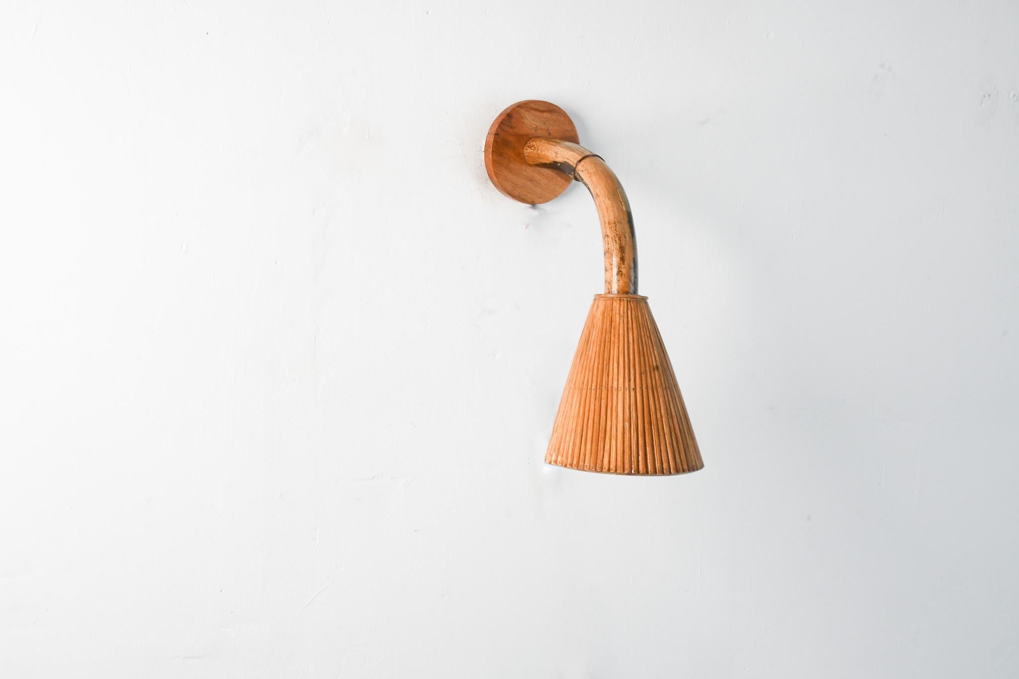 Questa applique moderna in stile Mid-Century è sapientemente realizzata con rattan a matita meticolosamente posizionato per creare un paralume delizioso, attaccato a un palo di rattan organico scavato in modo da creare questa lampada da parete