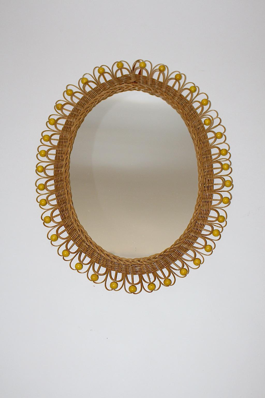 Rattan Willow organic Mid-Century Modern peacock wall mirror oval like 1970s Austria.
An oval wall mirror features a wrapped frame from rattan with yellow wooden pearls as amazing decor peacock like, while the rattan loops are slightly curved,
