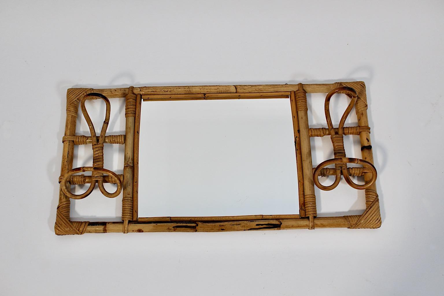 Riviera Style vintage organic bamboo rattan wall mirror with two ( 2 ) coat hooks 1950s Italy.
A stunning organic wall mirror rectangular like with coat hooks in beautiful brown color.
While the rattan frame is carefully cleaned, the mirror glass