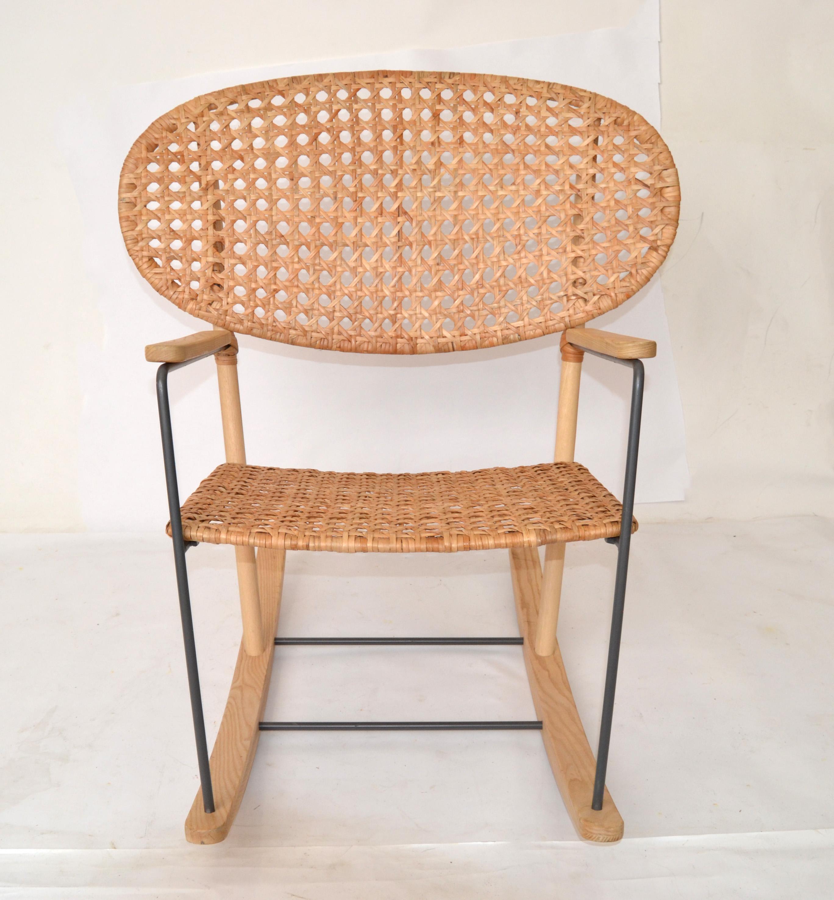 Scandinavian Modern rocking armchair made out of solid ash, steel frame and natural rattan weaving.
This rocking chair is a lightweight rocker made from handwoven rattan and ash colored wood. This airy rocker embodies modern Scandinavian design