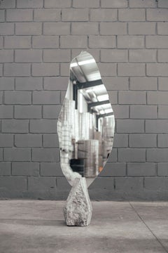 Miroir de forme organique avec base en pierre grise au centre par Andre Monnier