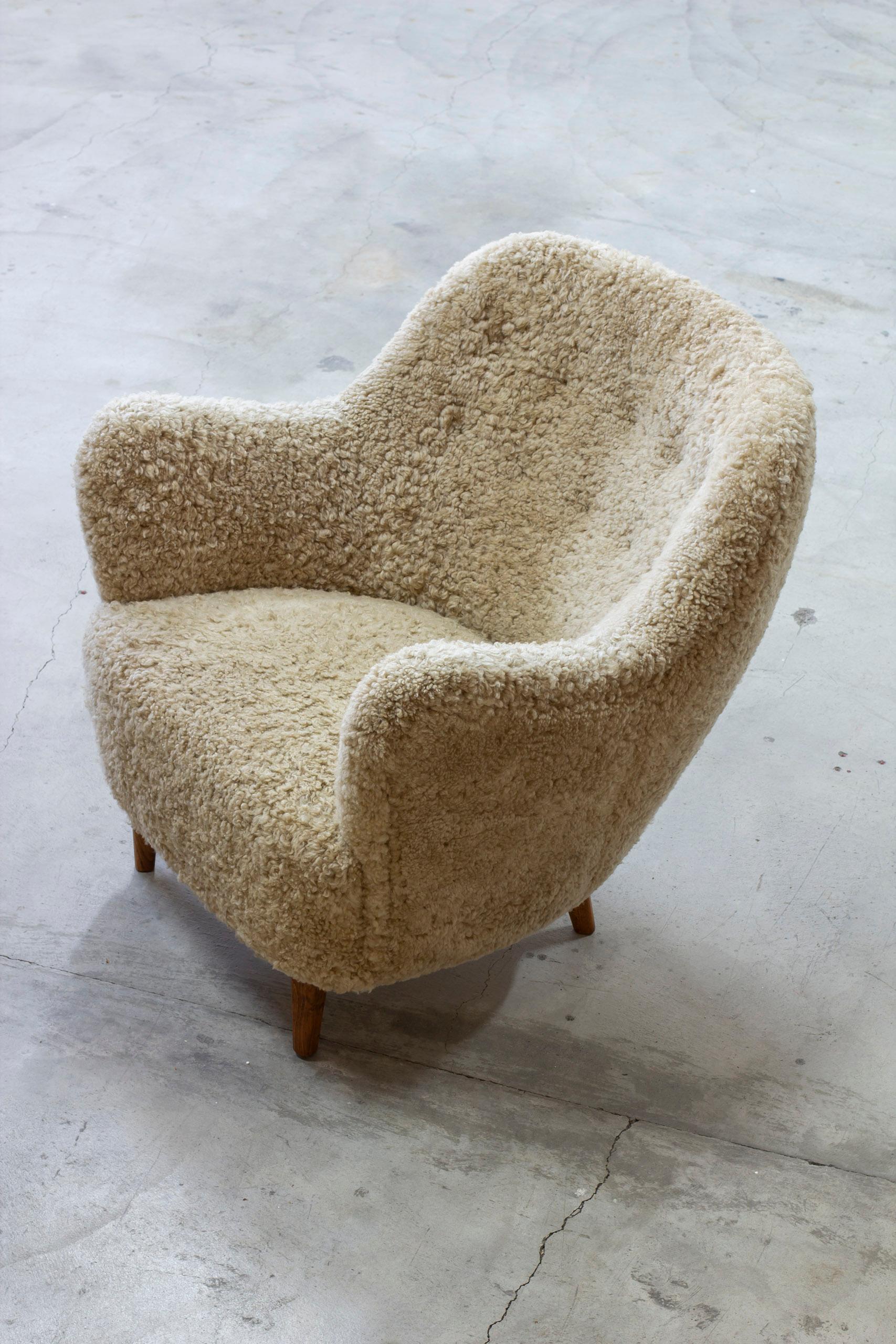 Organic lounge chair in the style of Finn Juhl. Made in Denmark by Unknown designer and craftsman during the 1950s. Large rounded shape and great comfort. Solid teak legs and new upholstery in beige sheep skin. Upholstered with whole sheep skins of
