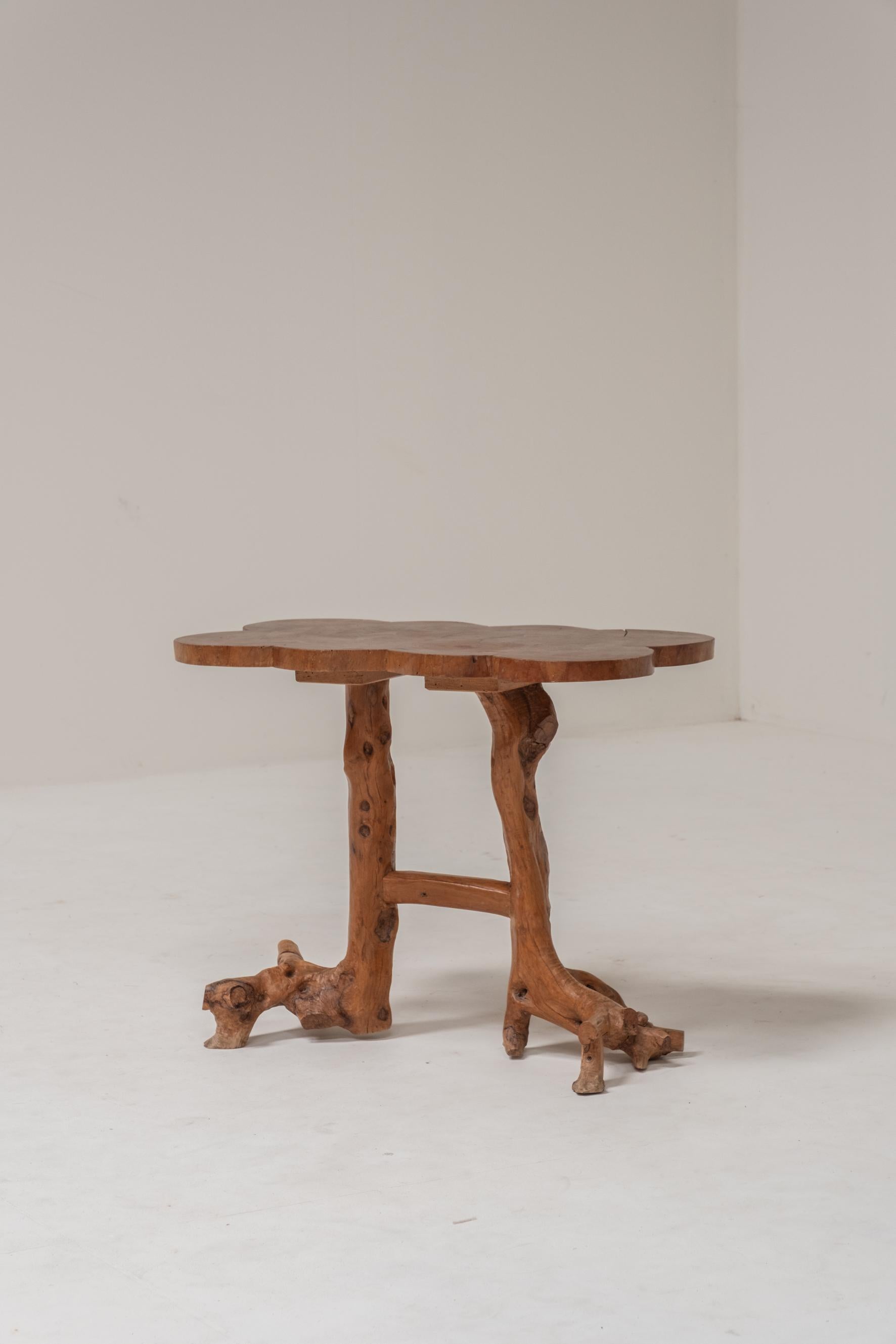 Charming handcrafted side table made entirely from solid wood, showcasing a beautifully organic, sculptural design. The table stands on a natural branch-like base, featuring irregular lines and natural textures that highlight its artisanal