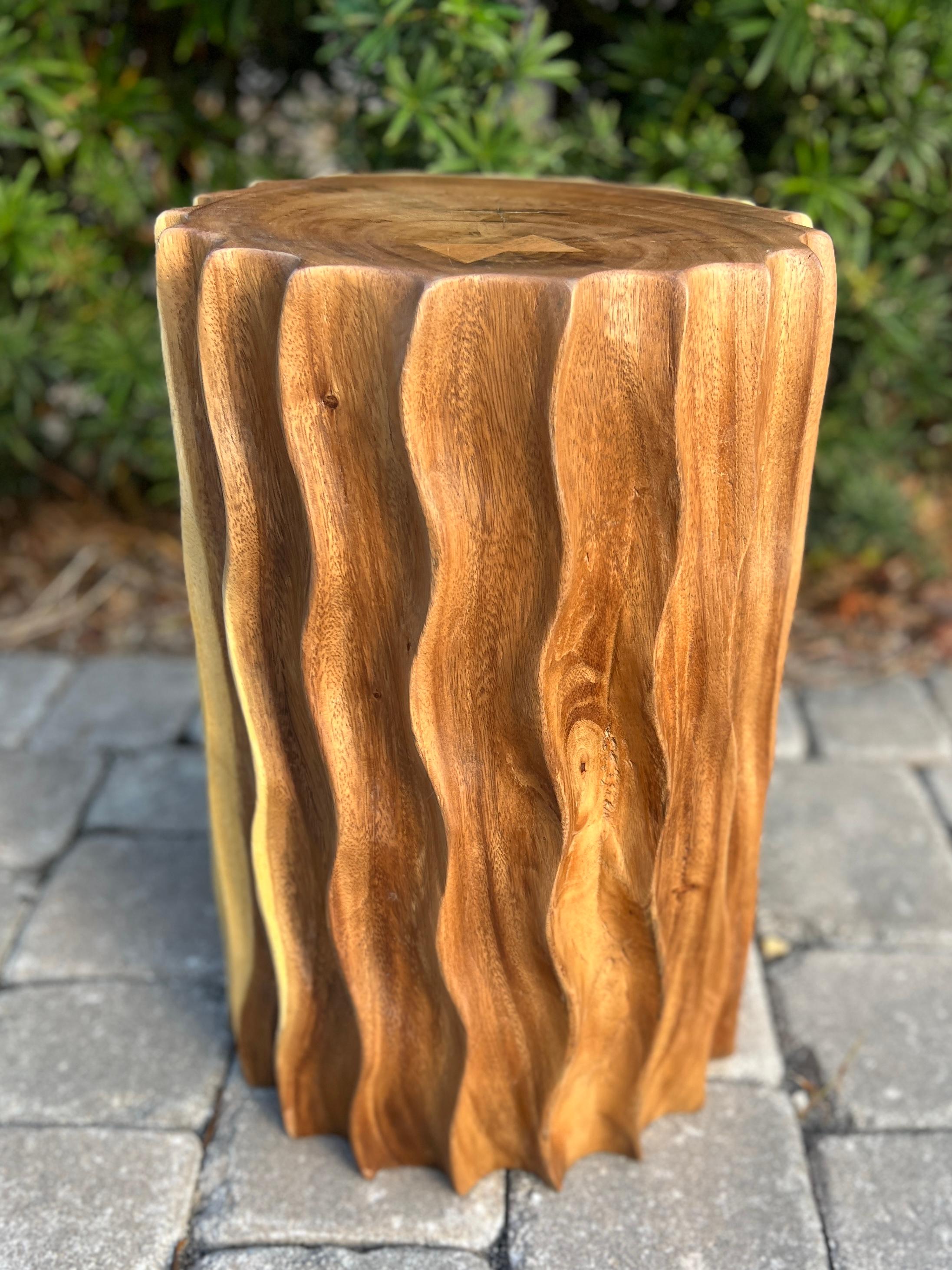 Sculptural drum side table comprised of reclaimed suar wood featuring hand-carved fluted sides with wave formation.  This versatile piece can also be used as a stool or a pedestal. Each table is uniquely handcrafted and features variegated hues of