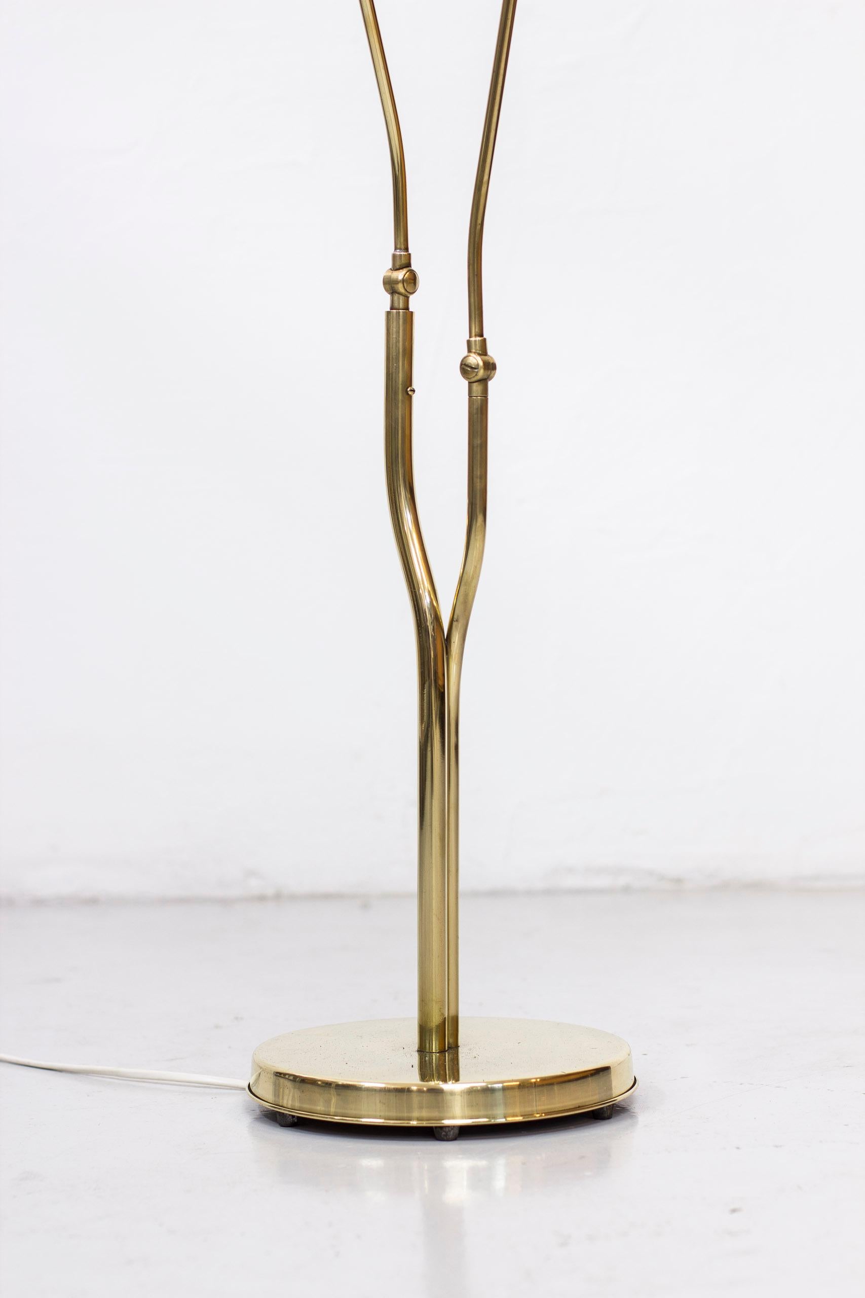Two-armed Swedish modern floor lamp. Made in Sweden during the 1940s. Made from polished brass with new hand sewn box pleated shades in chintz fabric. The lamp features a tree like stem with asymmetrical brass pipes with different dimensions.
