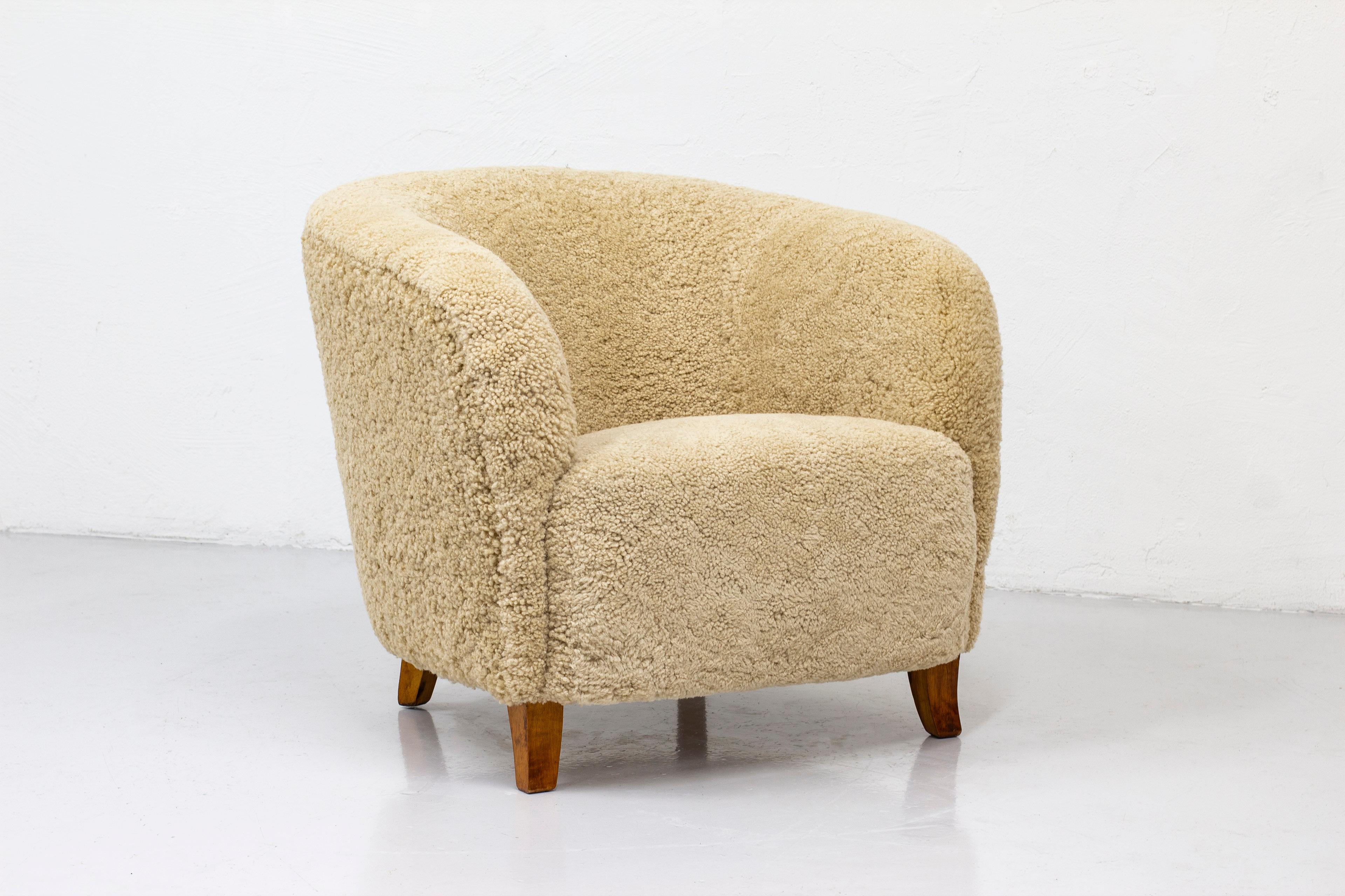 Swedish modern lounge chair designed and produced in Sweden during the 1940s. Chunky organic layout with slightly curved legs in beech wood. reupholstered with beige sheep skin. Very good vintage condition with light patina on the legs. Upholstery