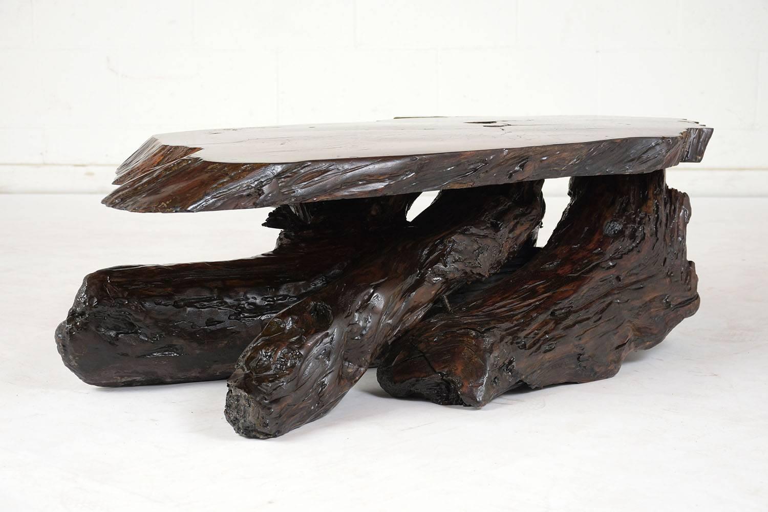 This organic style coffee table is made of walnut wood that dates to the 1900s. The tree root legs are very sturdy and hold up a slab with a live edge finish. The table is stained a deep walnut color with a lacquered finish. This coffee table is