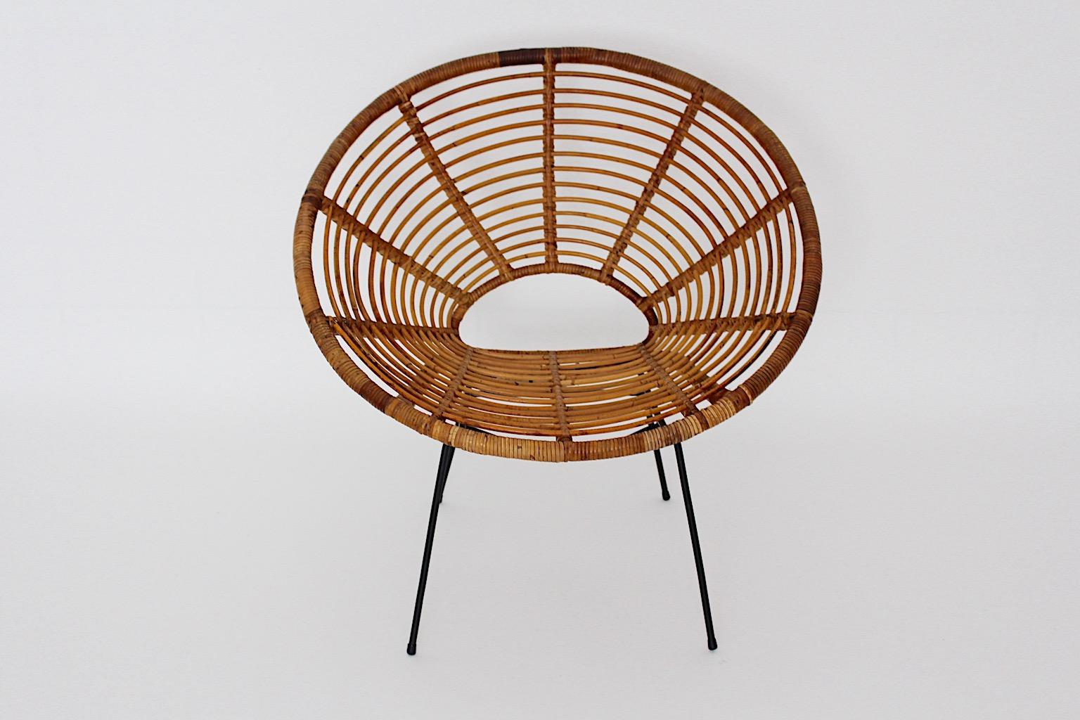 Organic rattan vintage four ( 4 ) dining chair patio chairs Riviera style France 1950s.
A fantastic set of four ( 4 ) rattan lounge chairs or dining chairs with a comfortable rattan seat shell and a stable black lacquered metal frame. 
The high