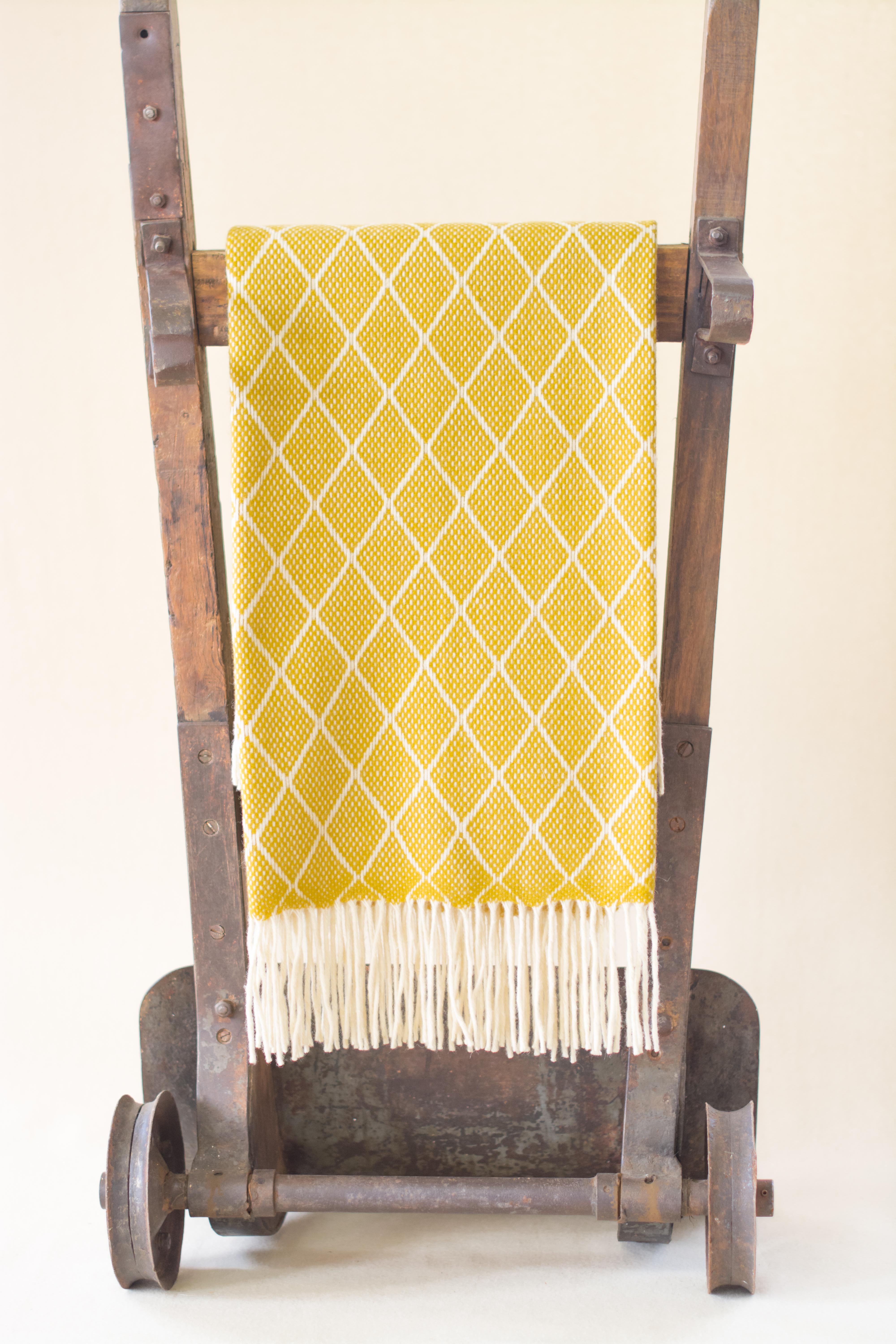 The Otilia yellow diamond pattern blanket or throw has been created by an incredible and unique family owned weaving and textile company in Portugal. This company impressed us so much by their commitment to working with the environment, their