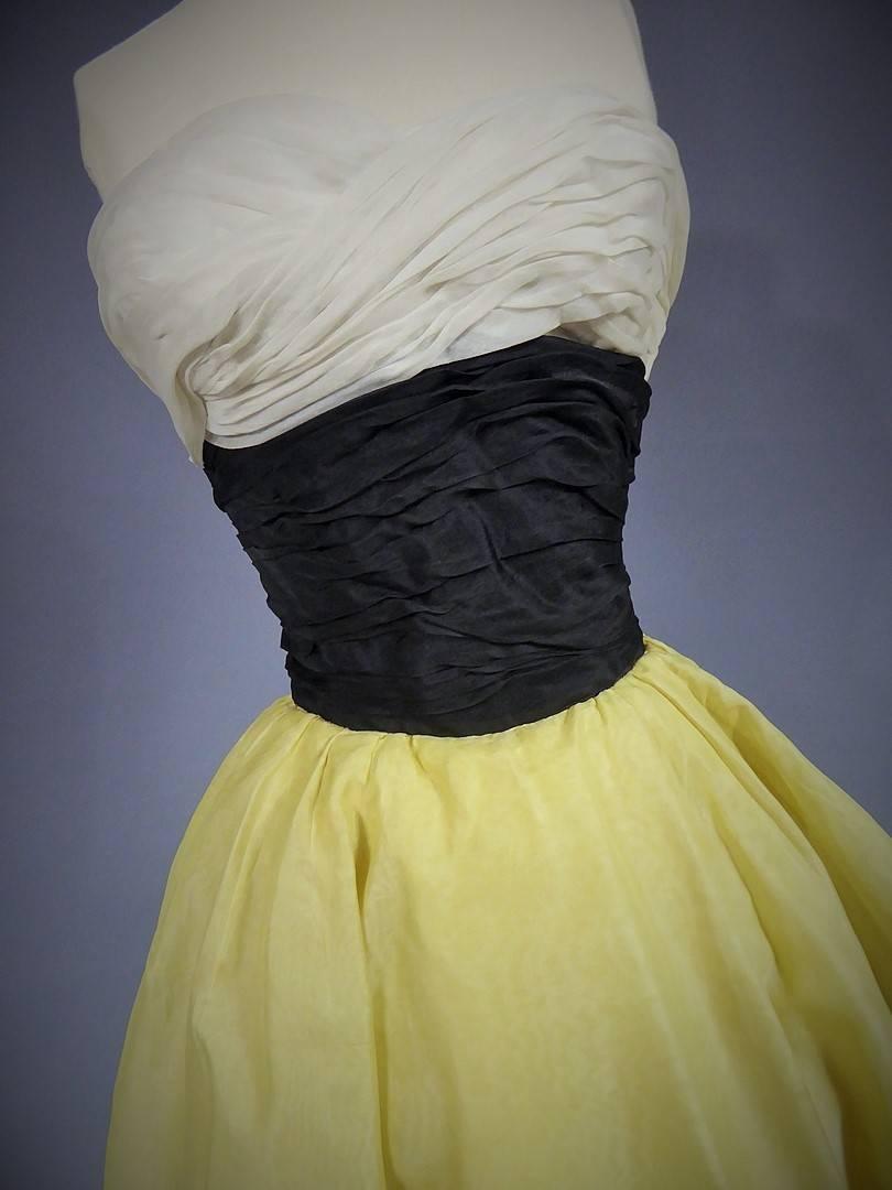 Circa 1955
France 

Elegant evening or cocktail dress in organza, unidentified Haute Couture from the 1950s. Bodice with low-cut neckine, halterneck, marked waist and loose skirt, give to this dress an air of New Look. Cream and black silk organza