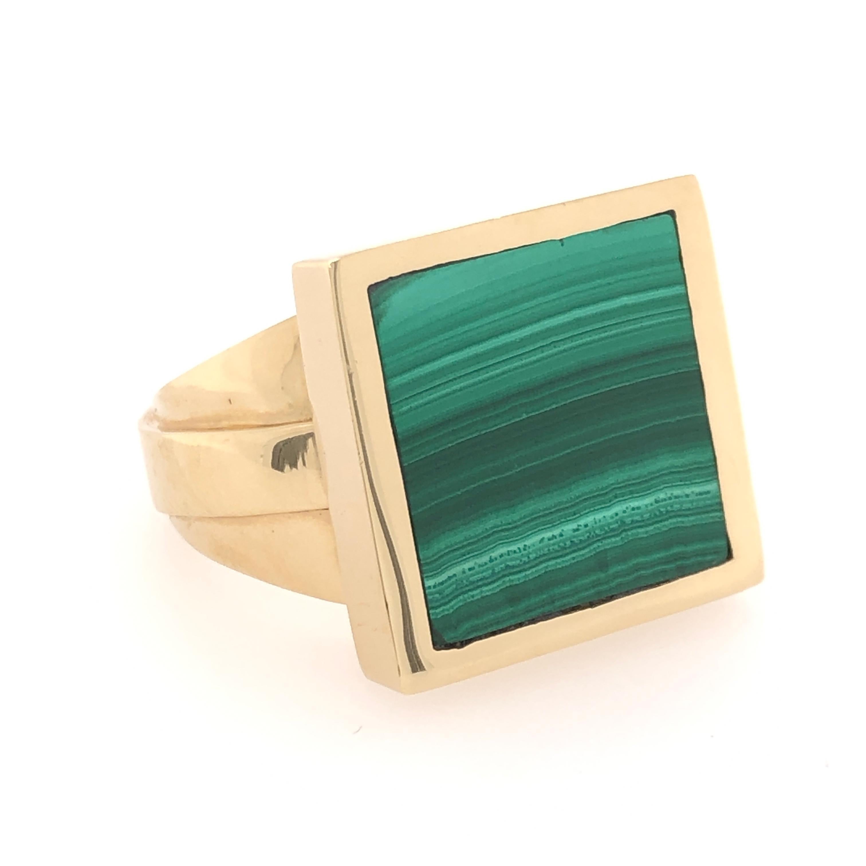 Gentlemen, if you like a little bit of color with the weight of a solid, study ring this 18 karat yellow gold malachite ring is for you. The varying green values in the natural striations of the this handsome stone compliment the angular design of