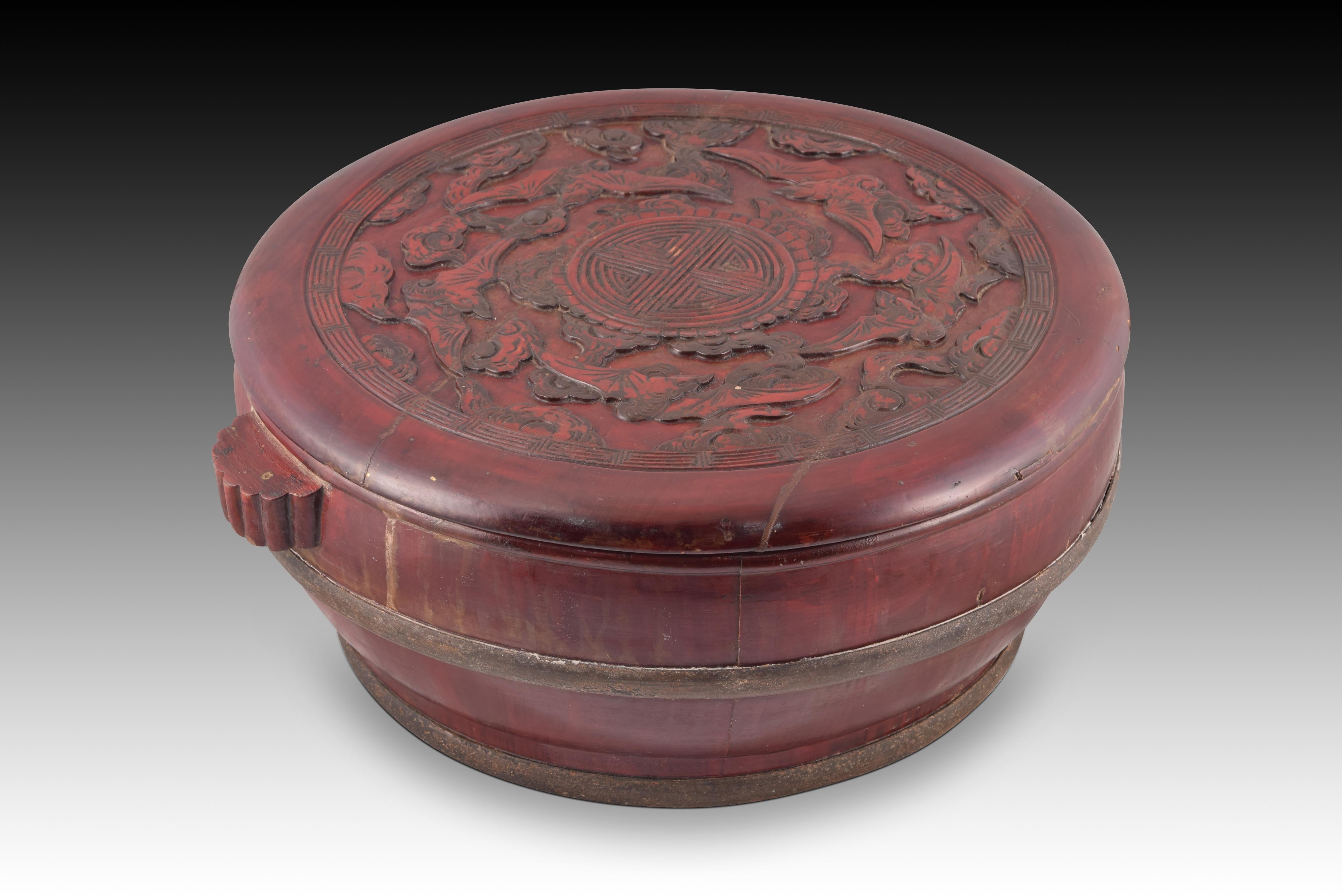 Oriental basket or box. Carved and lacquered wood, etc. Around 1950, possibly China.
 Container with lid with two small handles with a circular base decorated in red and with a carving of figurative elements on the upper part of the lid. Both in the