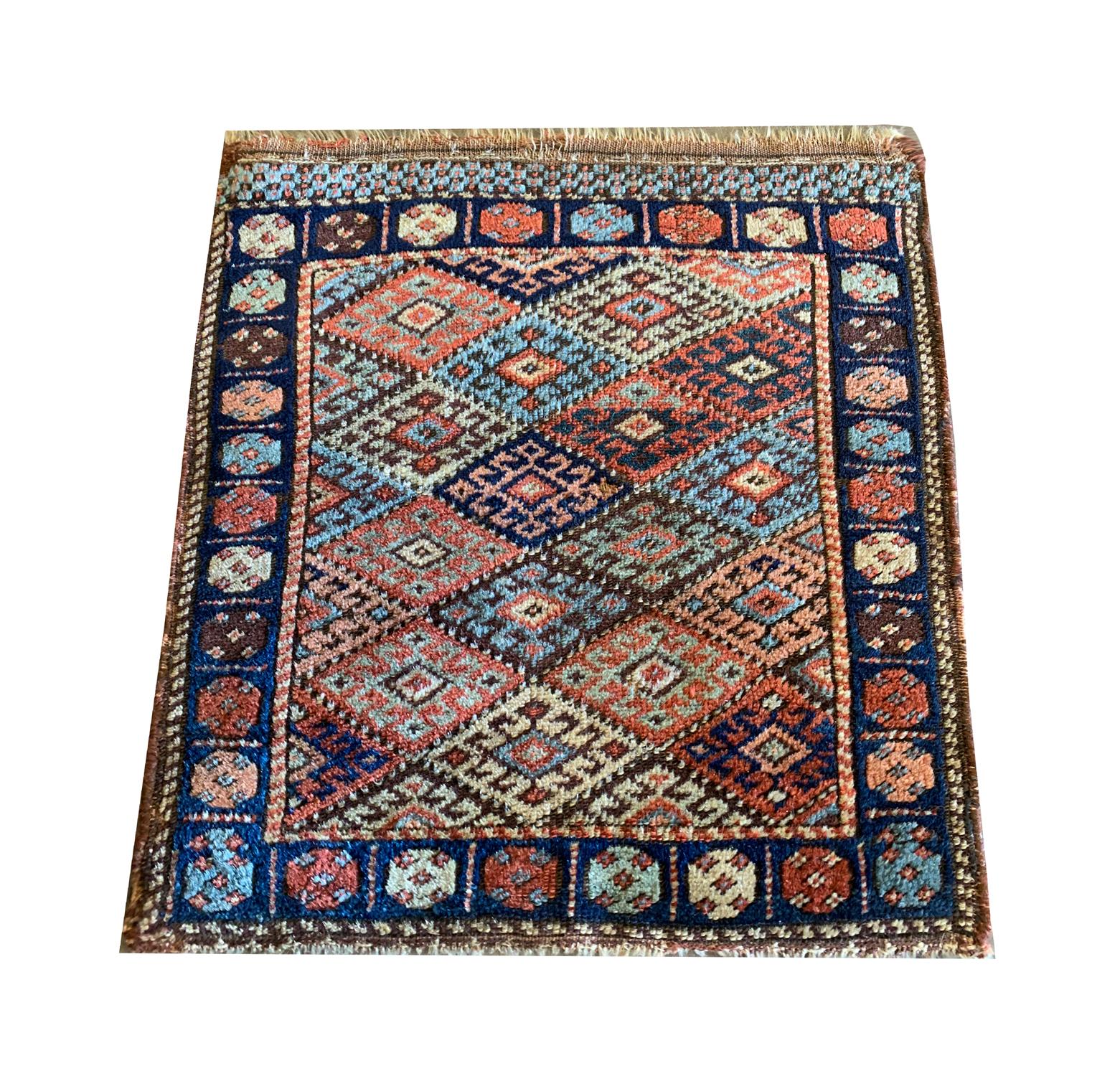 This small antique wool rug was woven by hand in Azerbaijan in the 1880s with the finest locally sourced materials. The central design features traditional hook motifs woven in a repeat geometric diamond pattern, in accents of orange, blue, green,