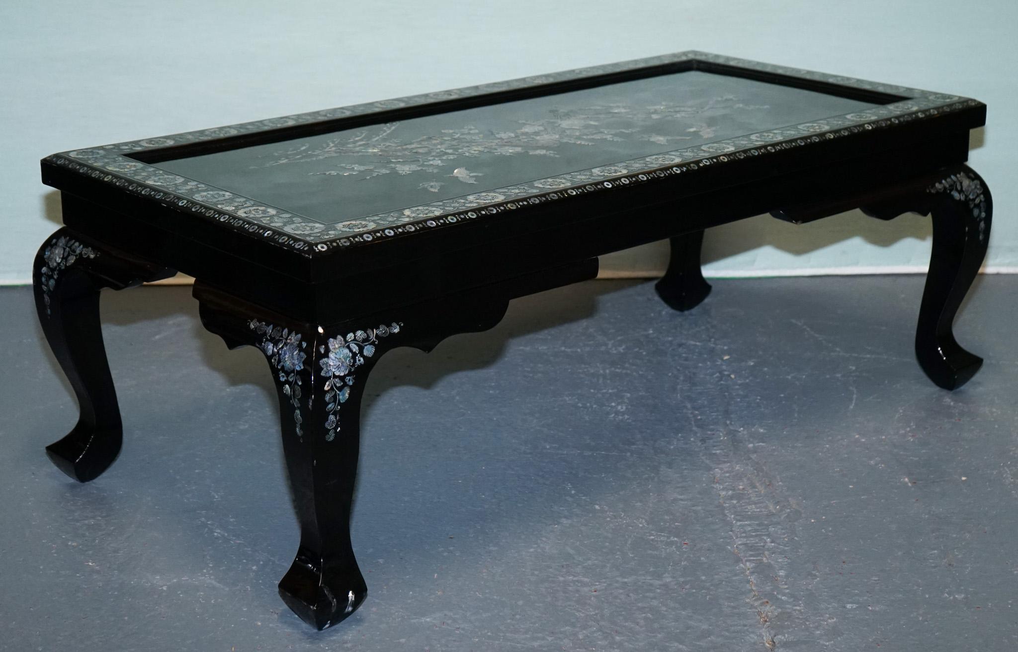 
Antiquitäten aus London



Ein eleganter orientalischer Couchtisch im Vintage-Stil aus reichem schwarzem Lack, wunderschön verziert mit komplizierten Perlmutt-Intarsien. Die Tischplatte zeigt ein zartes Blumen- und Vogelmotiv, umrahmt von einem