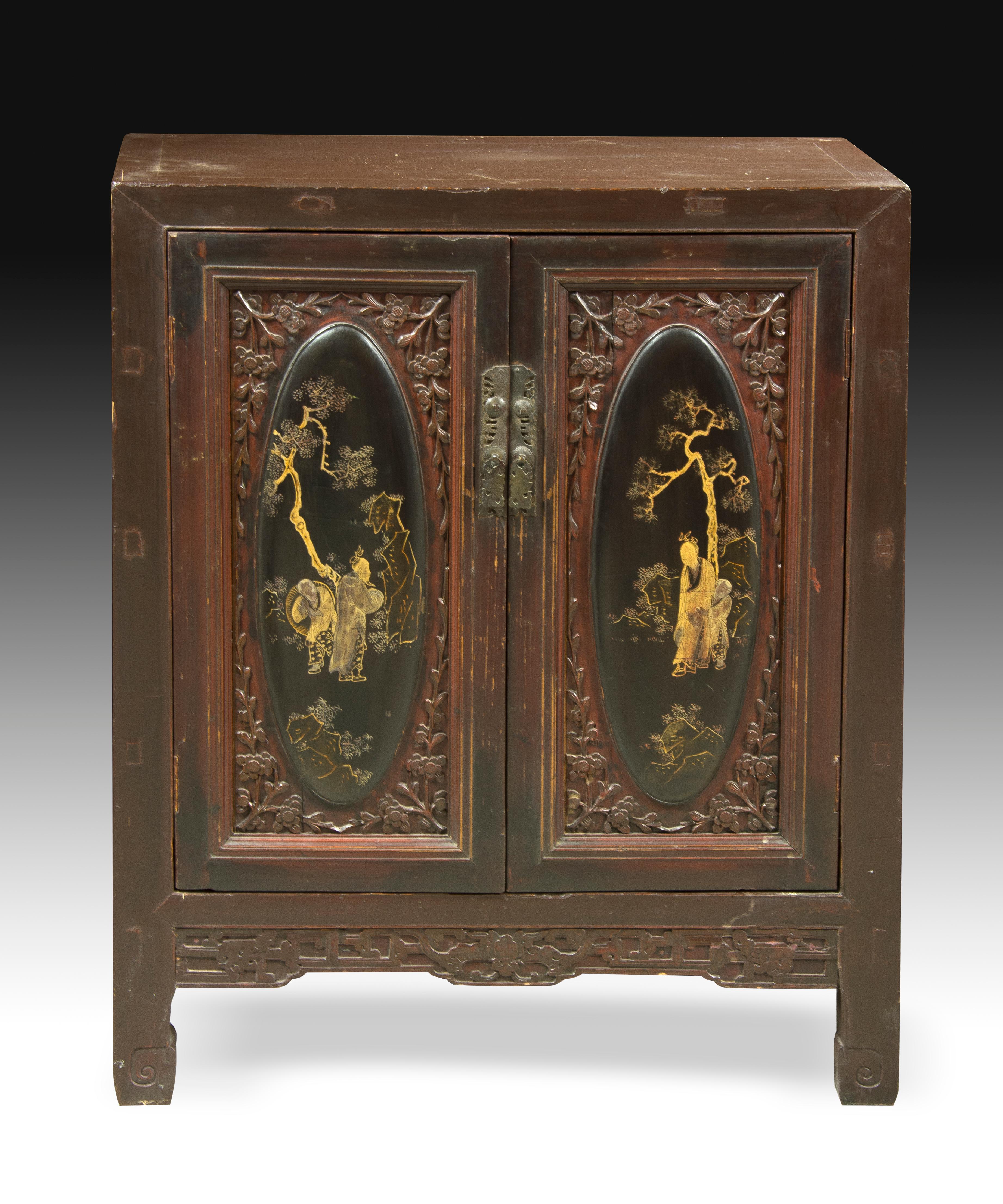 Wooden furniture decorated in its two front doors with oval figurative scenes (idealized landscapes and characters in gold on a black background) enhanced by frames with floral elements in relief, a band of sizes on the bottom and small details on