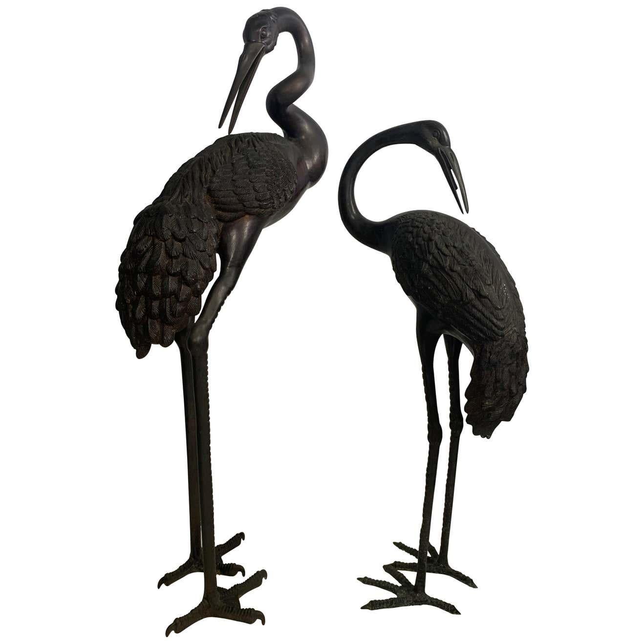 A pair of large bronze oriental cranes. A symbol of longevity and wisdom in oriental mythology, the crane is also considered to be the intermediary between earth and heaven. Measures: Male crane- height 55 (inches), width 21 (inches), depth 9