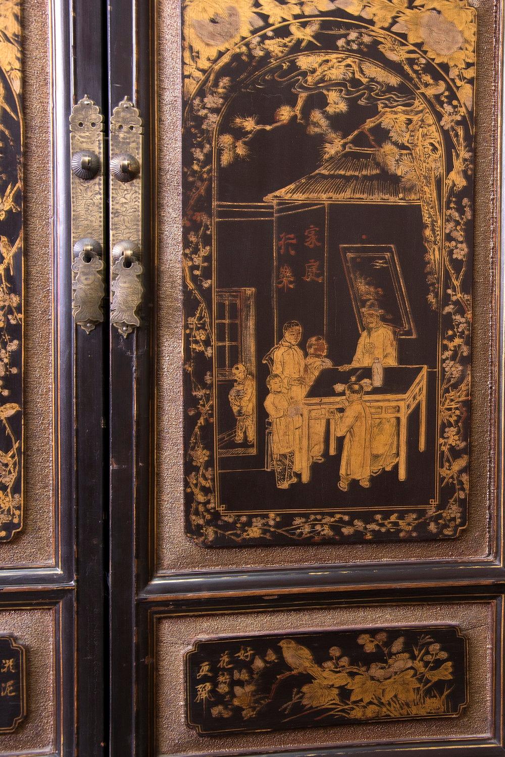 Wardrobe with two bodies, with two doors and two drawers in each (larger the upper ones), decorated on the sides with red stripes framing rectangular areas in dark tone, and, on the front, with pieces of lacquered wood with figurative scenes and
