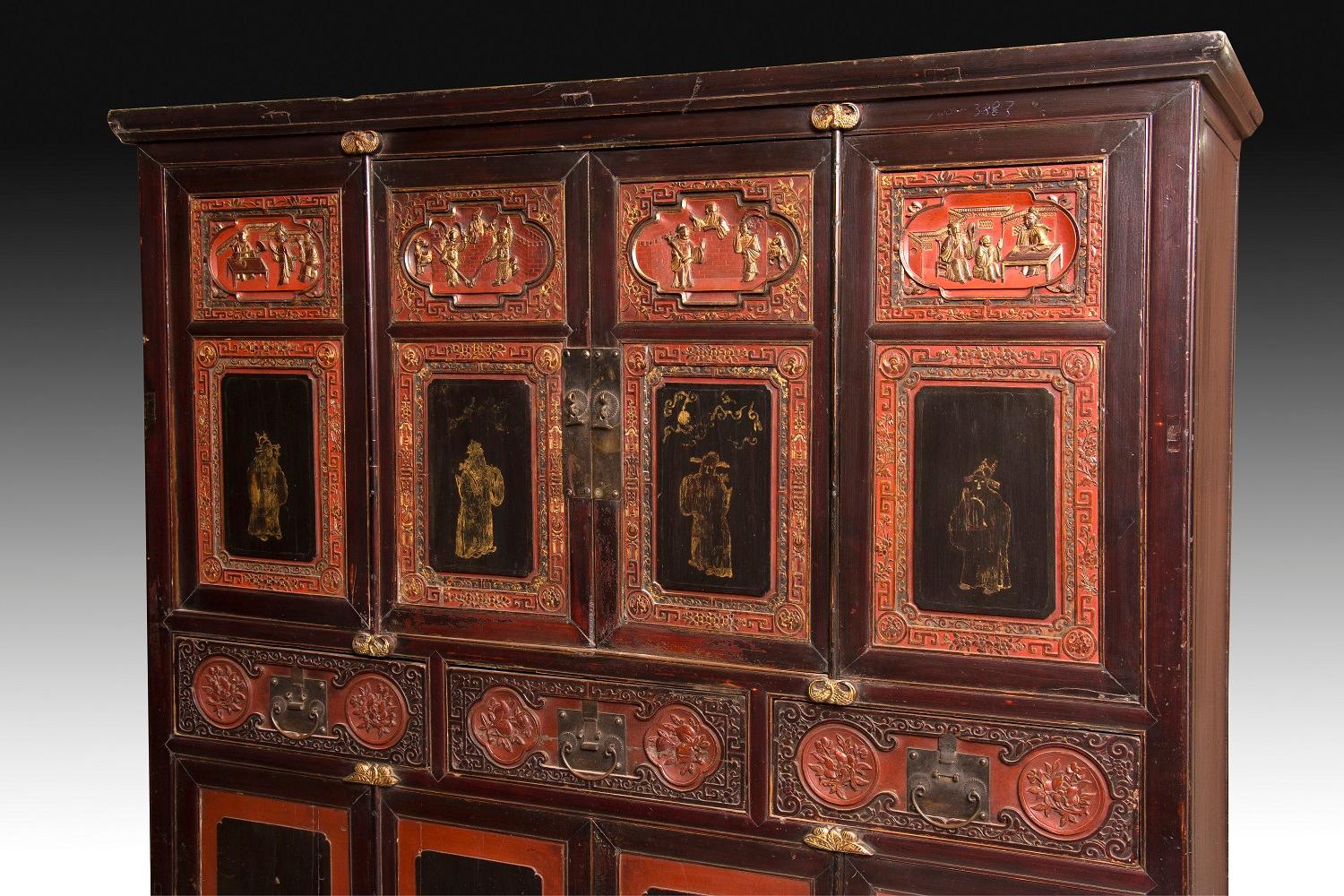 Wardrobe with four bodies and double height made of carved wood, polychrome and gold, rectangular, slightly raised on legs and topped by a simple molding. The lack of decoration on the sides leaves the prominence that deserves a very worked front: