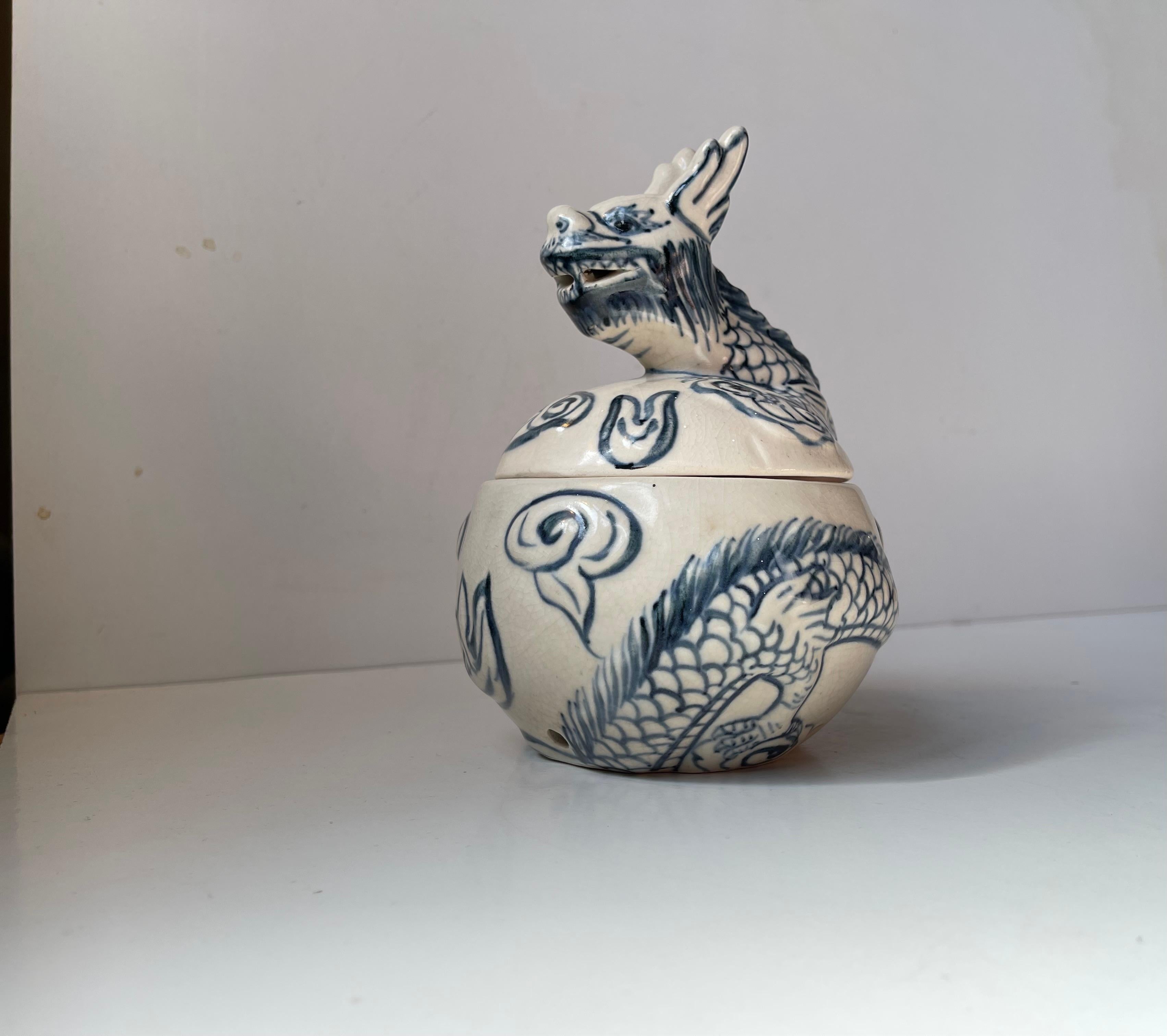 Ein möglicherweise vietnamesisches Porzellangefäß. Dekoriert mit einem skulptierten Drachen - handbemalt, eher naiv, mit blauer Glasur. Vor allem die Innenseite des Deckels lässt auf ein gewisses Alter schließen (braune Patina - Wäsche?/Patina). Der