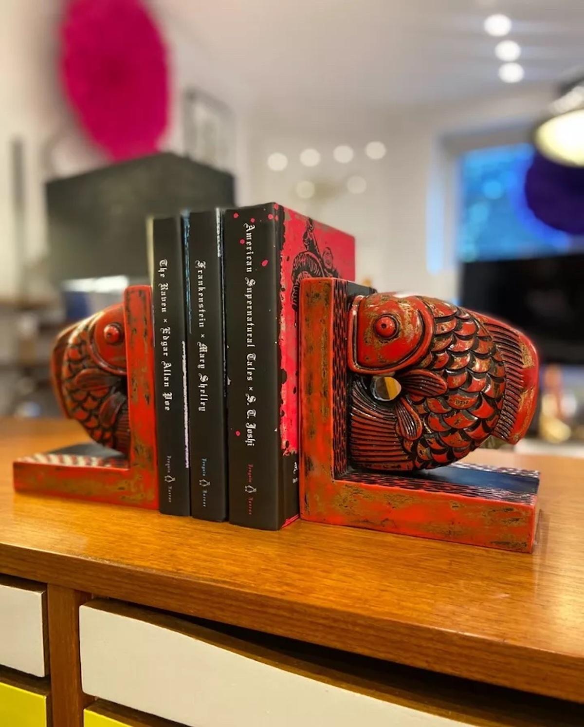 Este par de sujetalibros orientales de madera lacada en rojo y negro con forma de pez cola de abanico es a la vez práctico y decorativo. Altamente detalladas con una artesanía intrincada, estas llamativas piezas hacen una declaración audaz,
