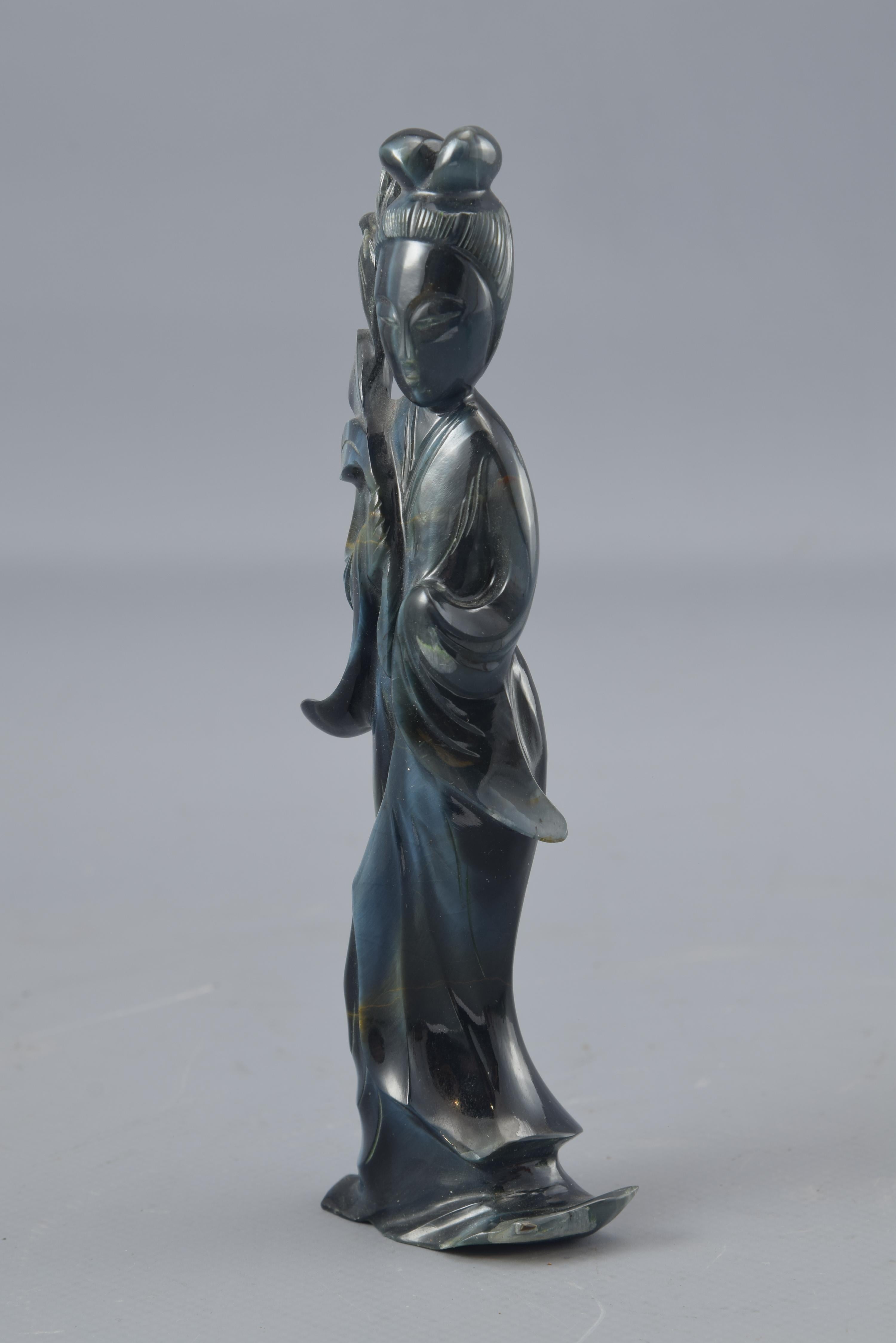 Stylized figure made of hard stone with a dark tone, with a vein in lighter colors that perhaps represents one of the eight immortals of the Taoist pantheon, He Xiangu (who is usually shown holding a lotus flower, sometimes also accompanied by a