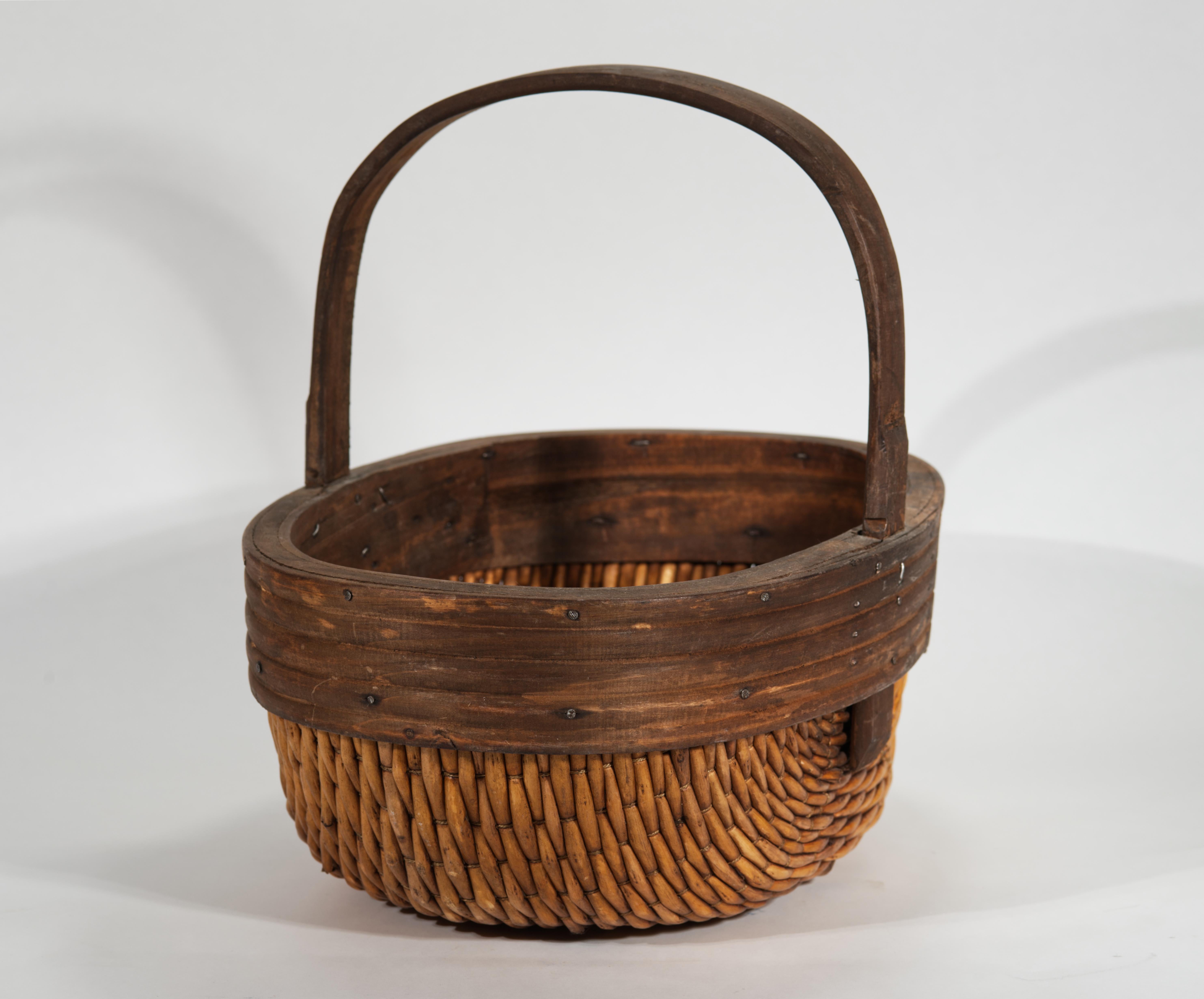 La cesta de pescador o de grano de estilo chino vintage presenta la forma tradicional con lados redondeados y borde de madera y asa grande. Las fuertes y flexibles tiras de mimbre o sauce están hábilmente tejidas en un delicado patrón que enfatiza