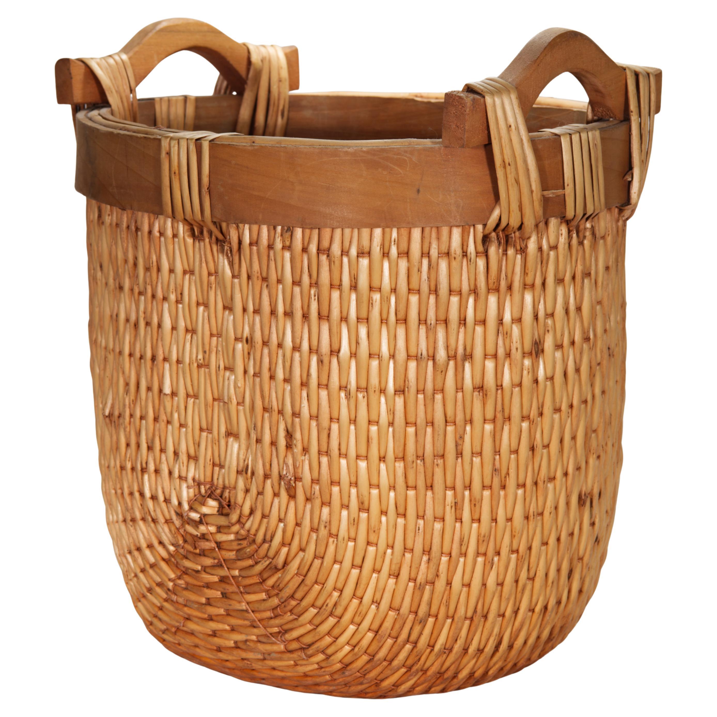 Ce panier de pêcheur ou à grains de style chinois vintage présente la forme traditionnelle avec des côtés arrondis, un rebord et des poignées en bois. Les bandes d'osier ou de saule, solides et flexibles, sont habilement tressées en un motif