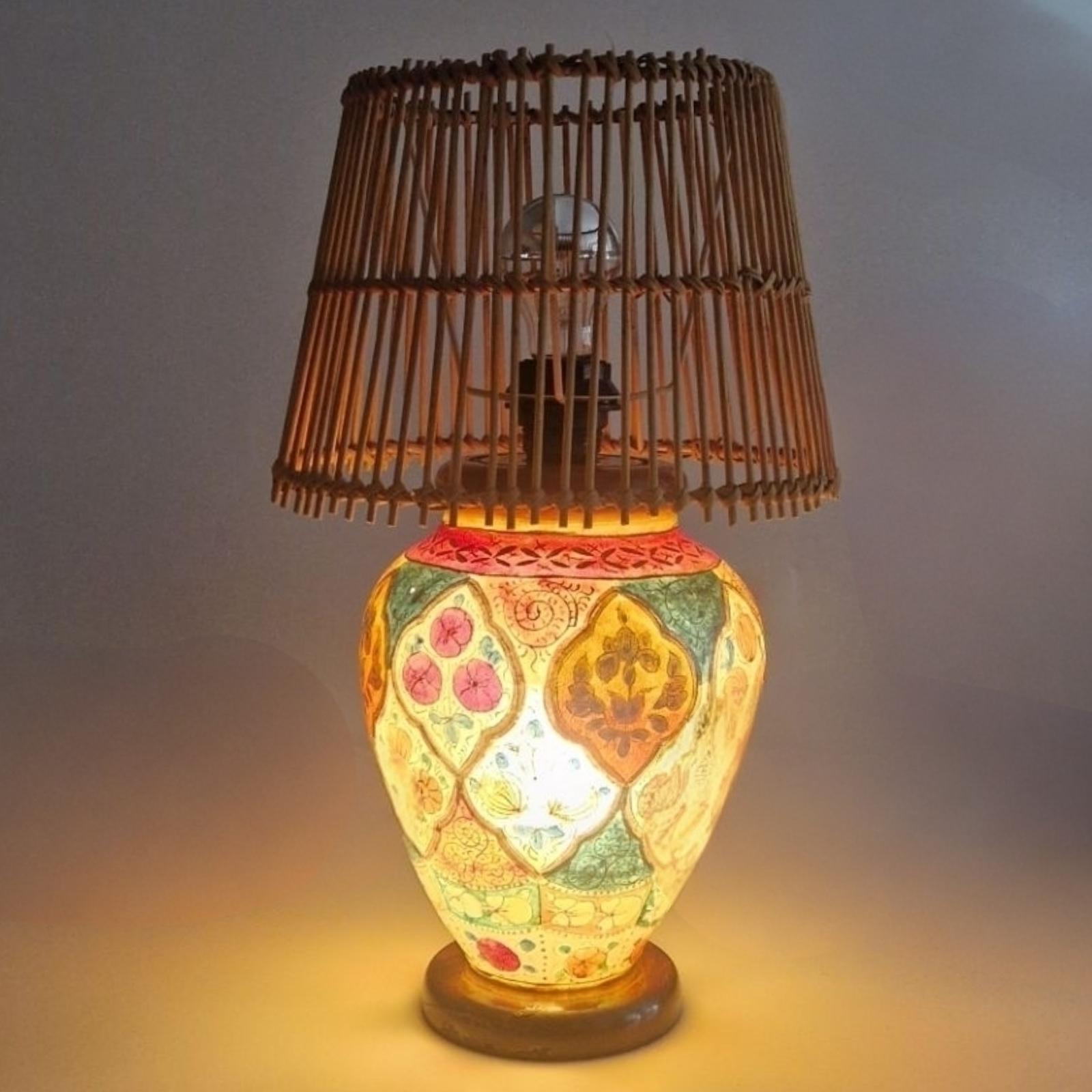 hand made and handpainted multicolored table lamp. The base is made from camel leather  and hardwood. It is hand painted with a floral decor. It has one light in the base shining through the leather. The shade is made from bamboo. 
The shade