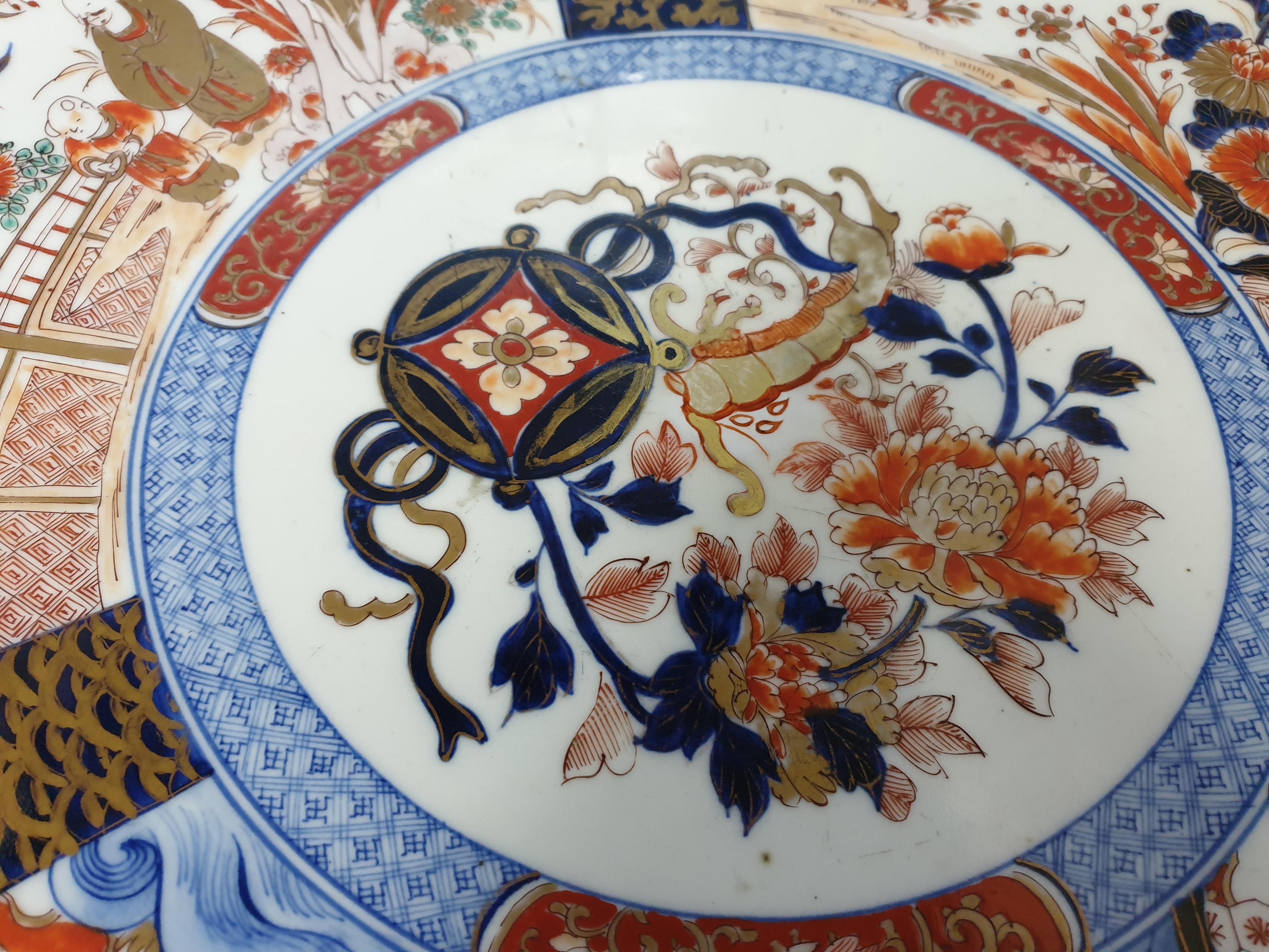 An extremely large Japanese Imari platter or charger Meiji period with paneled scenes and jeweled designs. The platter is very impressive and is divided into 3 panels each depicting a new view interspersed within scenes of nature. Each scene of the