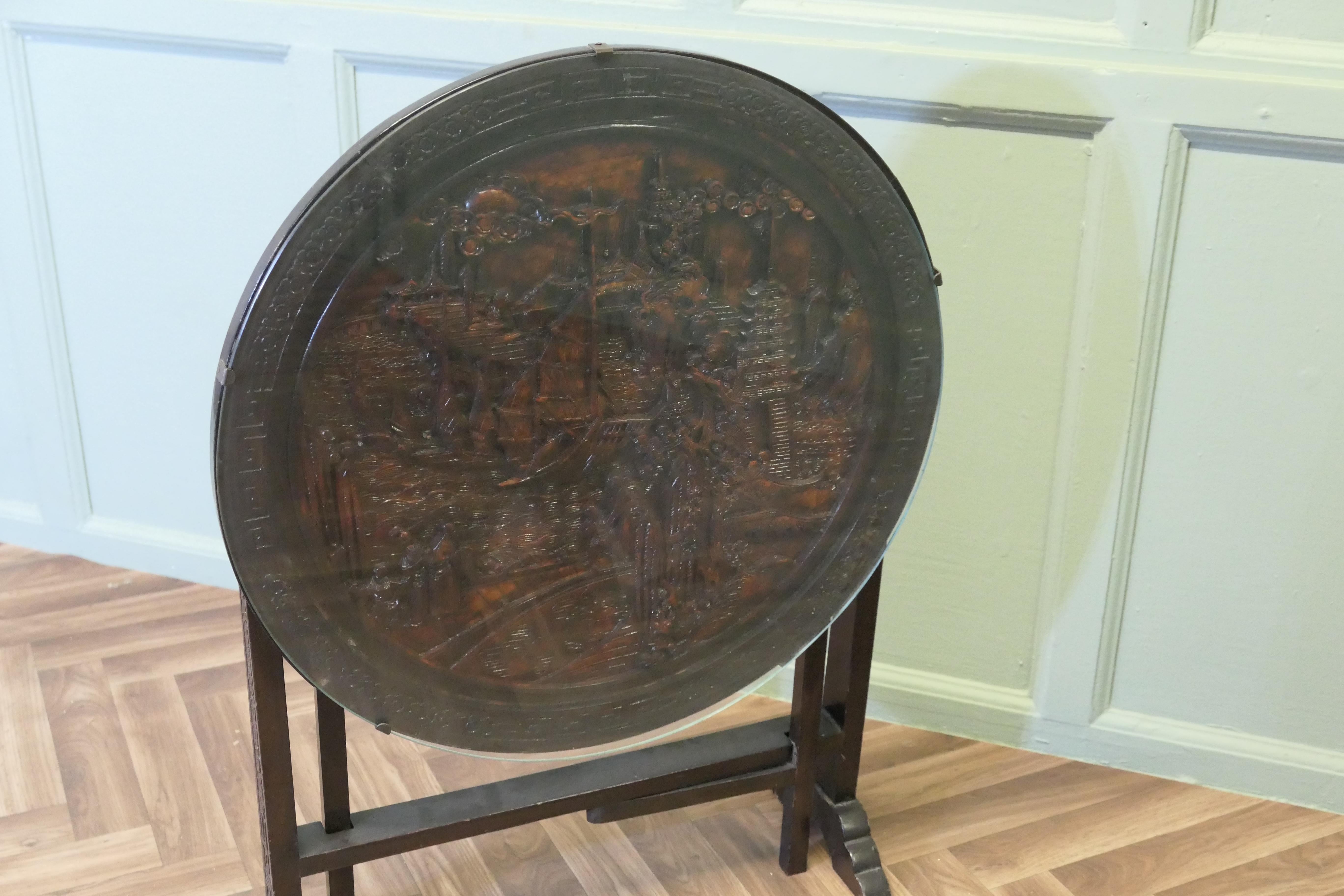 Oriental Metamorphic Fire Screen/Coffee Table

A Superb expertly hand carved Coffee table which tilts and can be turned into a very attractive fire screen
The top is carved with ships and pagodas, it has a protective plate glass cover
The table is