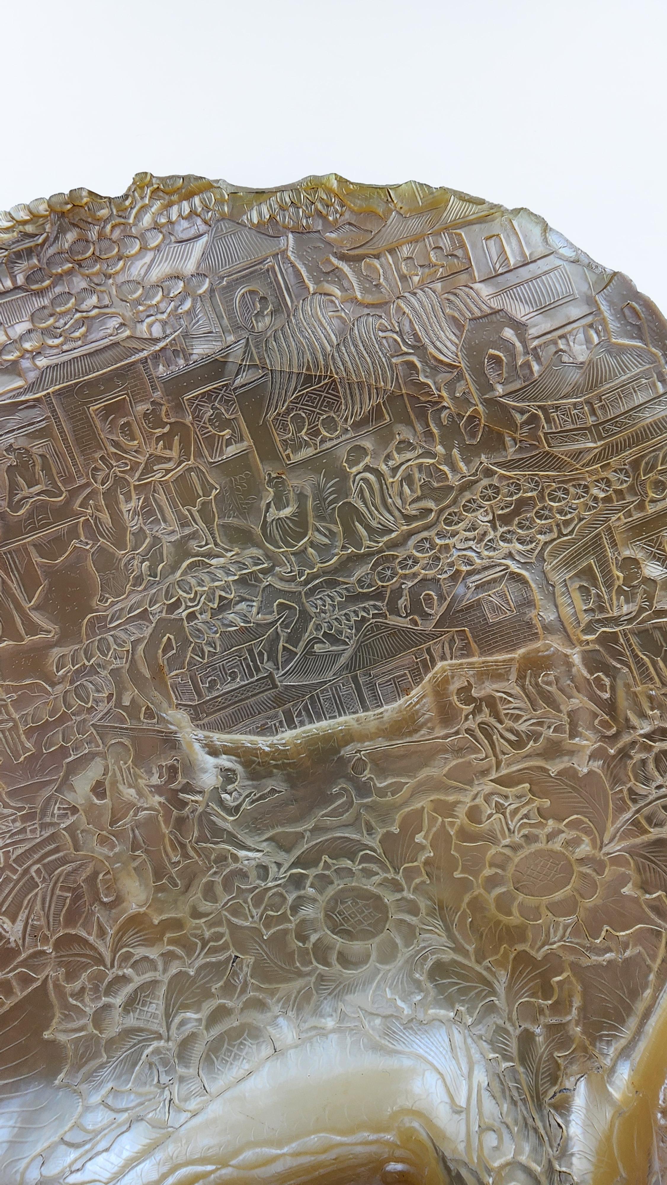 Nacre orientale sculptée en bas-relief
Coquille en nacre de forme irrégulière, sculptée en bas-relief de motifs orientaux détaillés. La surface intérieure irisée présente des teintes allant du crème à l'or, en passant par des touches nacrées. Le