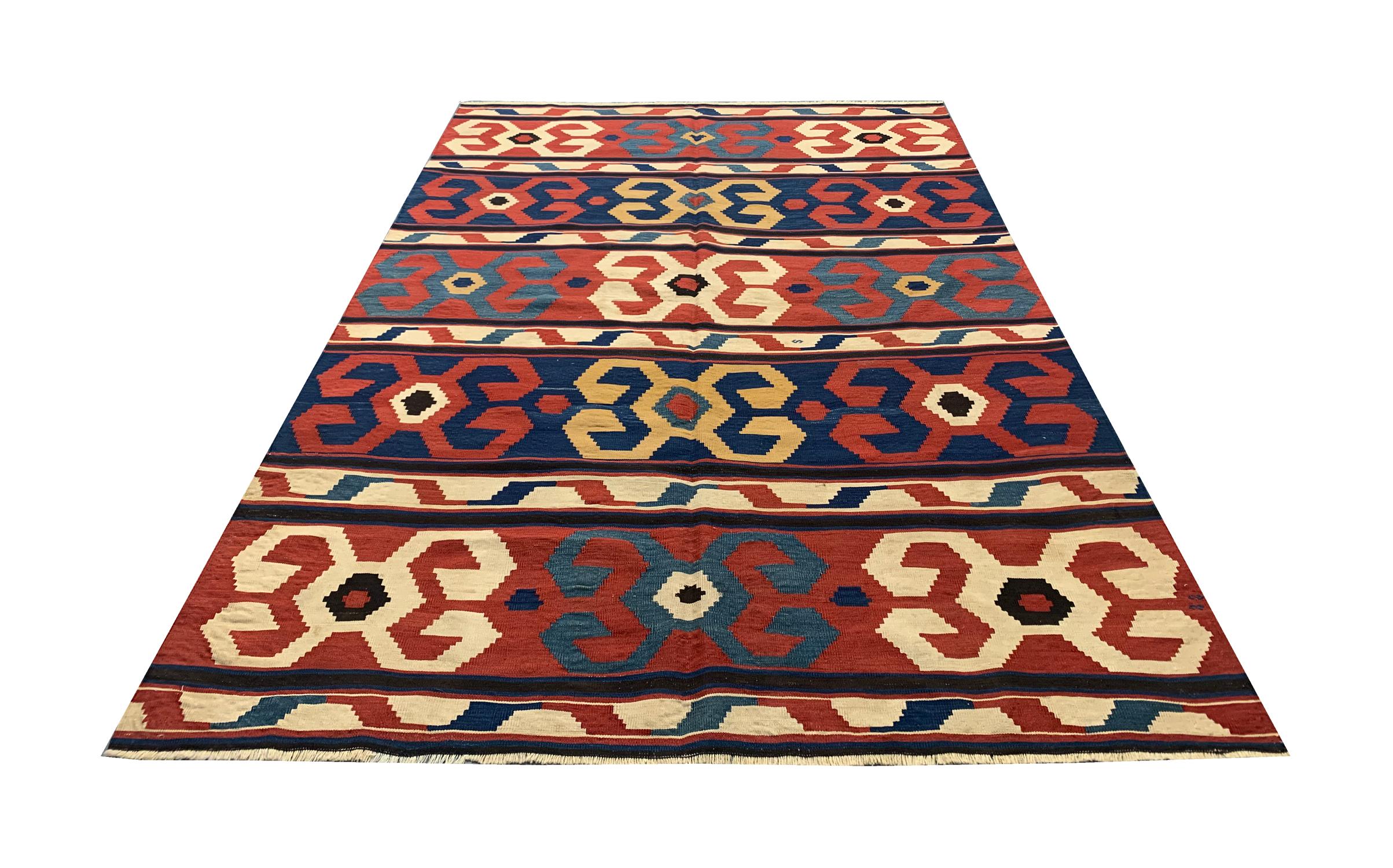 This antique Kilim has been woven to perfection on looms of master weavers of Caucasia in the 1920s. The design features a repeat motif pattern that has been woven by hand to create this all-over design. Red, cream and blue make up the main colours
