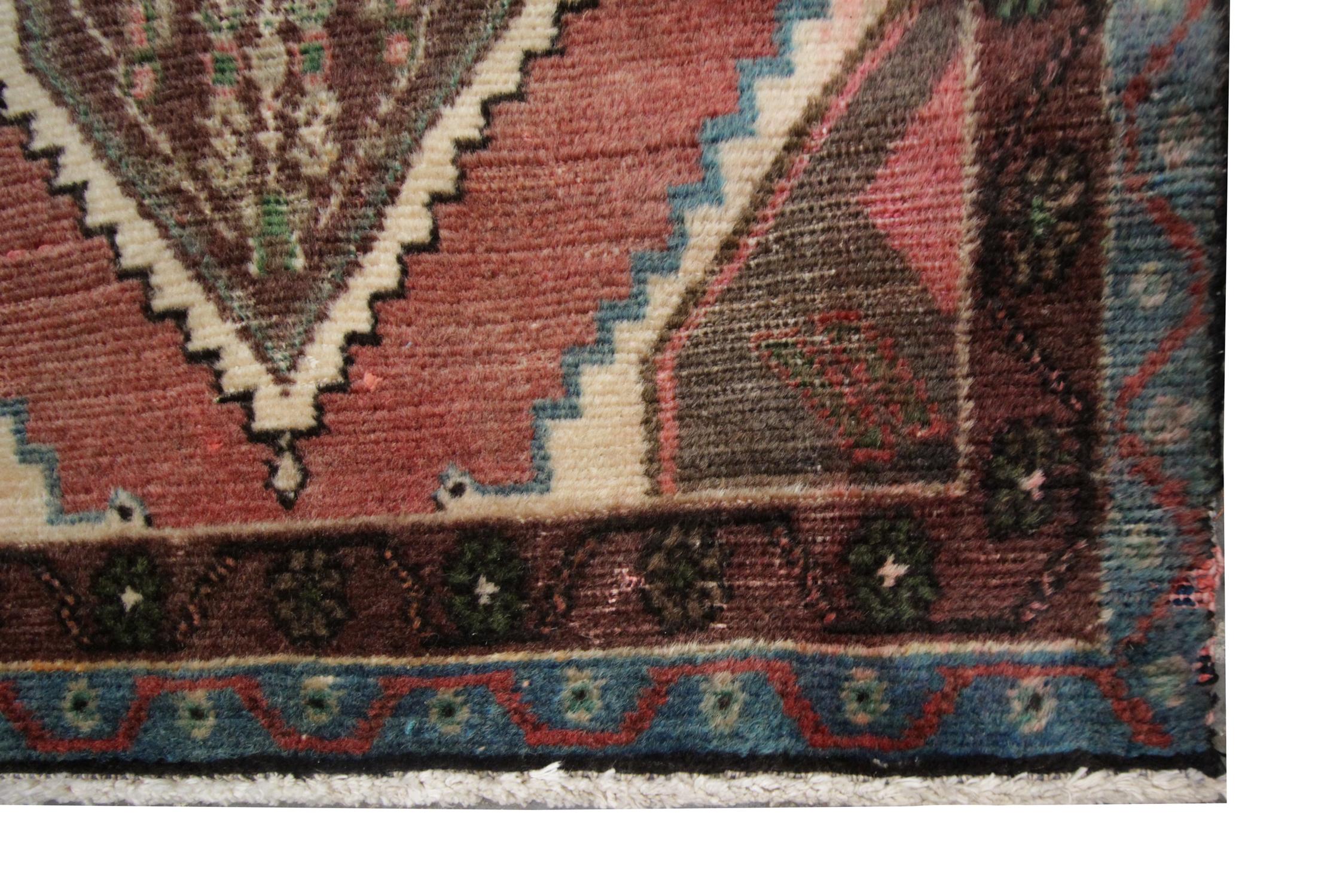 Browns and oranges sit woven in harmony in this geometric handmade carpet runner rug, featuring a repeat pattern of brown, detailed diamonds which sit on a background of red in this oriental rug. Further details show geometric motifs and zigzag