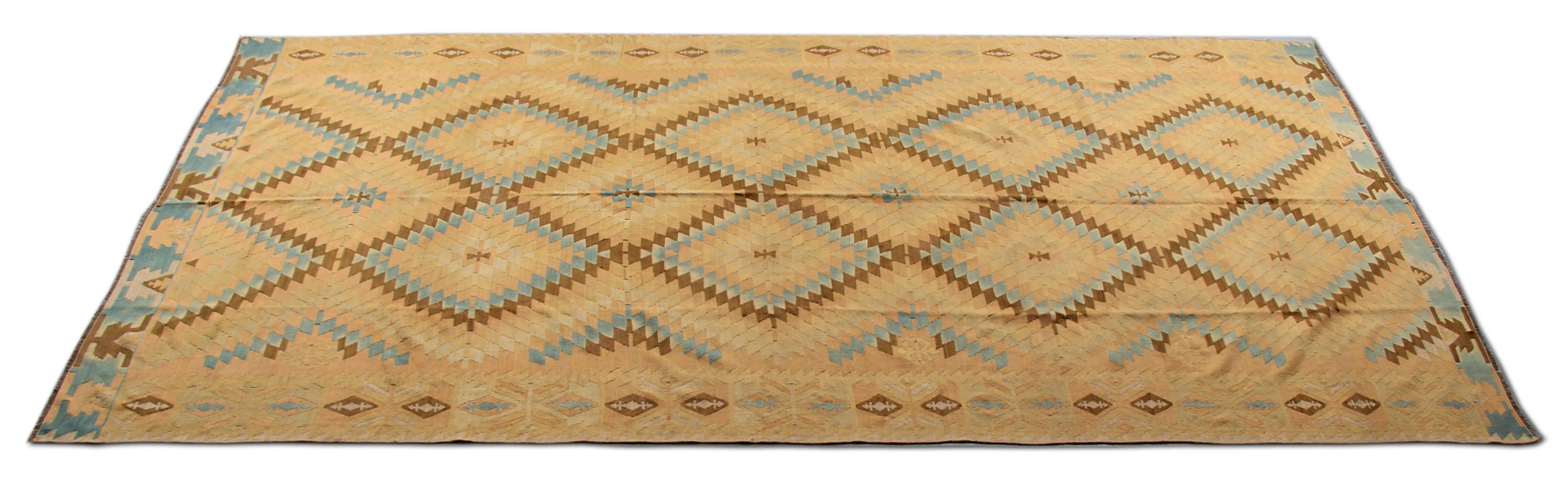 This stunning Kilim rug has been hand-dyed and hand-woven to create its unique colour and pattern. This Antique rug has a striking colour combination of yellow, navy, gold, cream and various shades of blue. This Kilim runner rug has clear influences