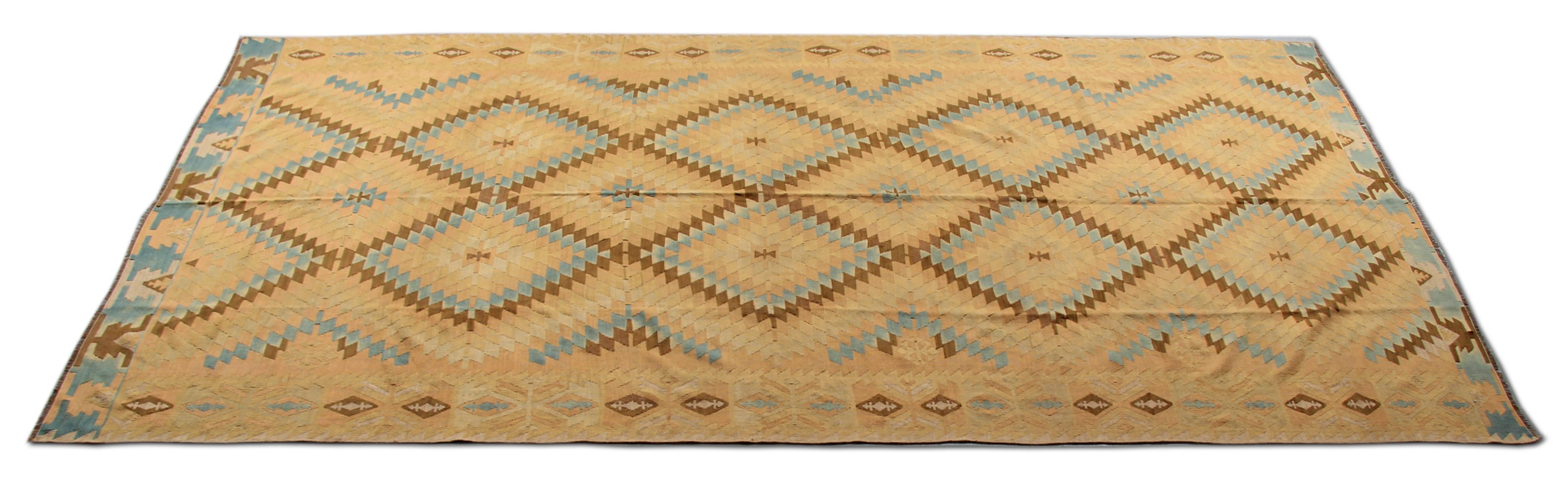 Questo splendido tappeto Kilim è stato tinto e tessuto a mano per creare colori e motivi unici. Questo tappeto antico presenta una straordinaria combinazione di colori: giallo, blu, oro, crema e varie tonalità di blu. Questo tappeto runner Kilim ha