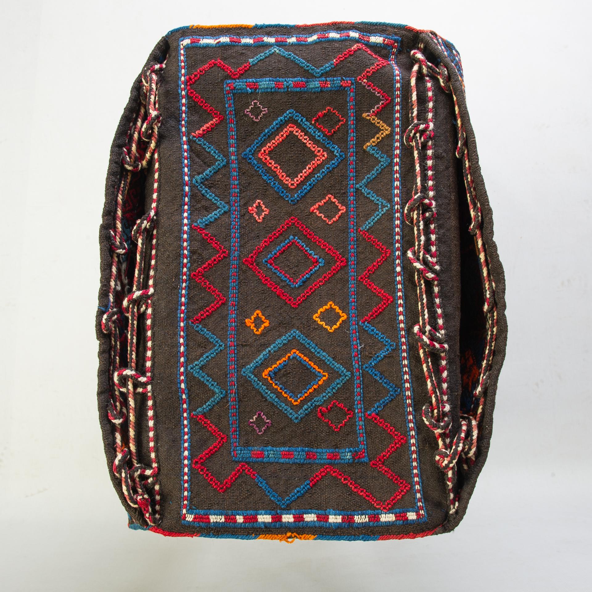 Doppelte Azeri-Satteltasche, auf dem Webstuhl gewebt und handbestickt.
Auf einem Sockel (einem Hocker oder einem einfachen Holzsockel) von mittlerer Größe (siehe Foto) dienen die beiden Seitentaschen als Behälter für Zeitungen oder anderes.
 Es