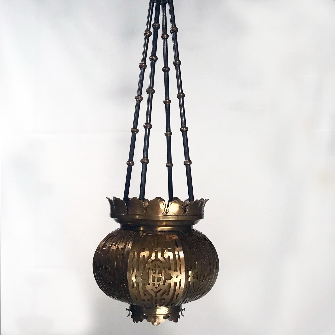 Antique brass oriental themed lantern, the compressed spherical body pierced with stylized designs, the crown and base modeled with leaves, with amber glass liner panels.