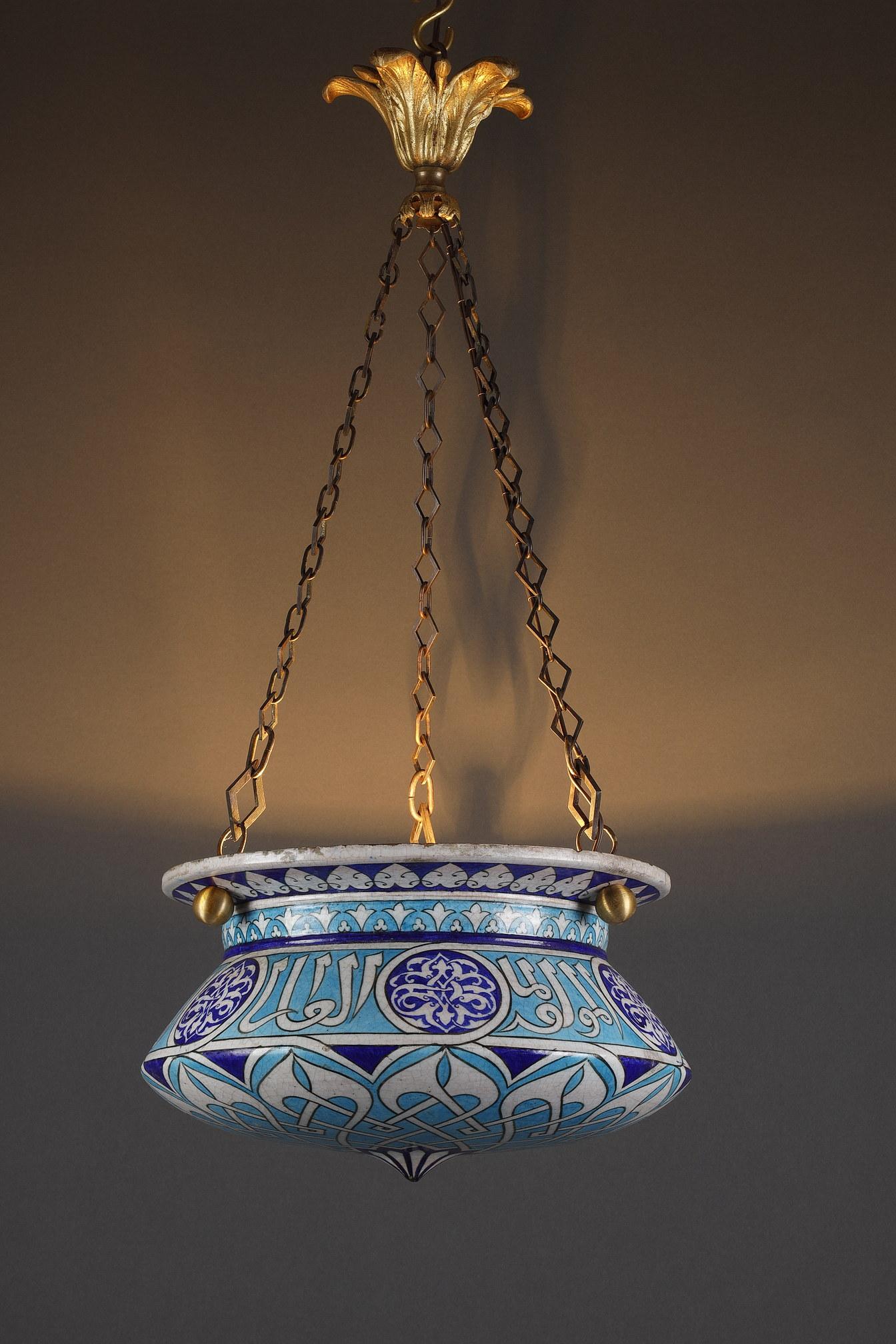Enameled ceramic chandelier with flared border underlined by a frieze of stylized foliage, decorated on the body with Arabic characters on a light blue background, alternating with tracery cartouches on a dark blue background, and white and blue