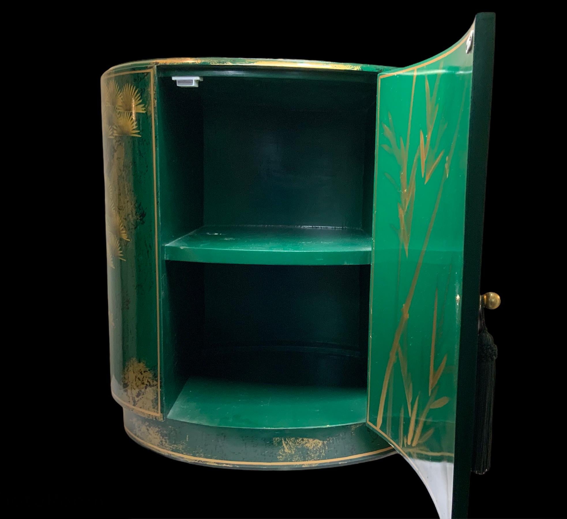 This is an oriental style large oval shaped shiny emerald green wood cabinet table. It is adorned with a continuous hand painted scene of a pair of large white-black cranes and gilt cedar bonsai trees. In the back of the door, it is adorned with