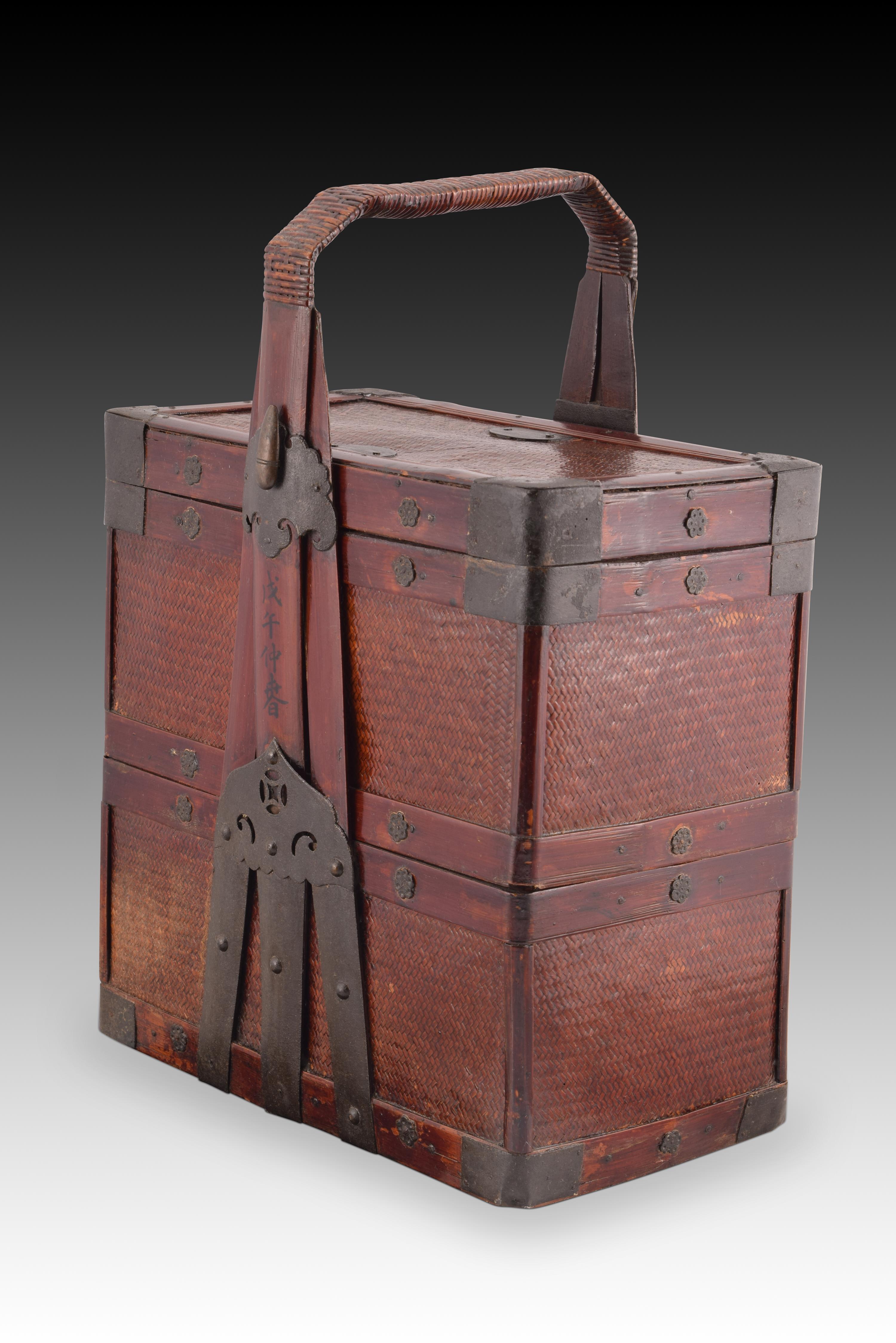 Oriental wedding basket. Vegetable fiber, wood and metal. China, early 20th century. 
Wedding basket with two articulated compartments, constructed using basket weaving and reinforced with wooden slats and cut-out and openwork metal fittings. With a