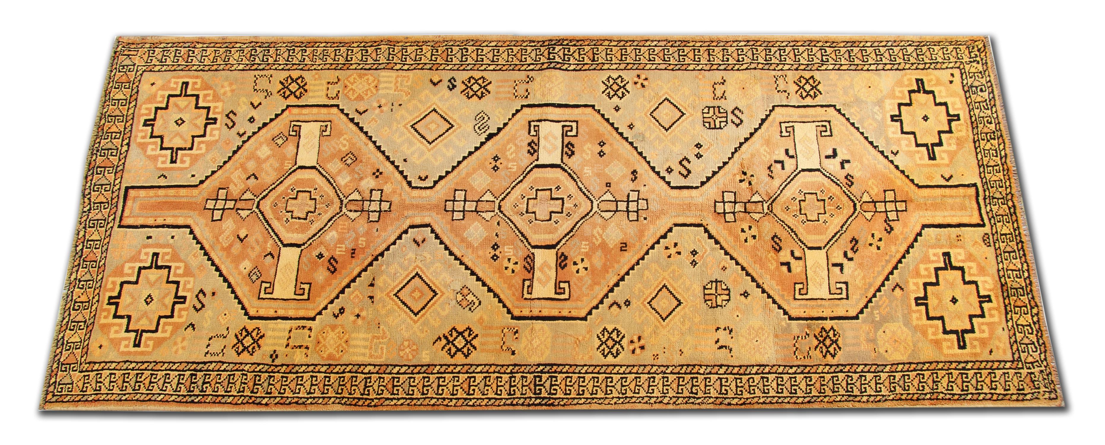 This unique wool runner rug is a vintage piece woven in the late 20th century. The design has been woven with a simple colour palette including rust, beige and black, with tribal motifs woven in a symmetrical pattern. The colour and the design in