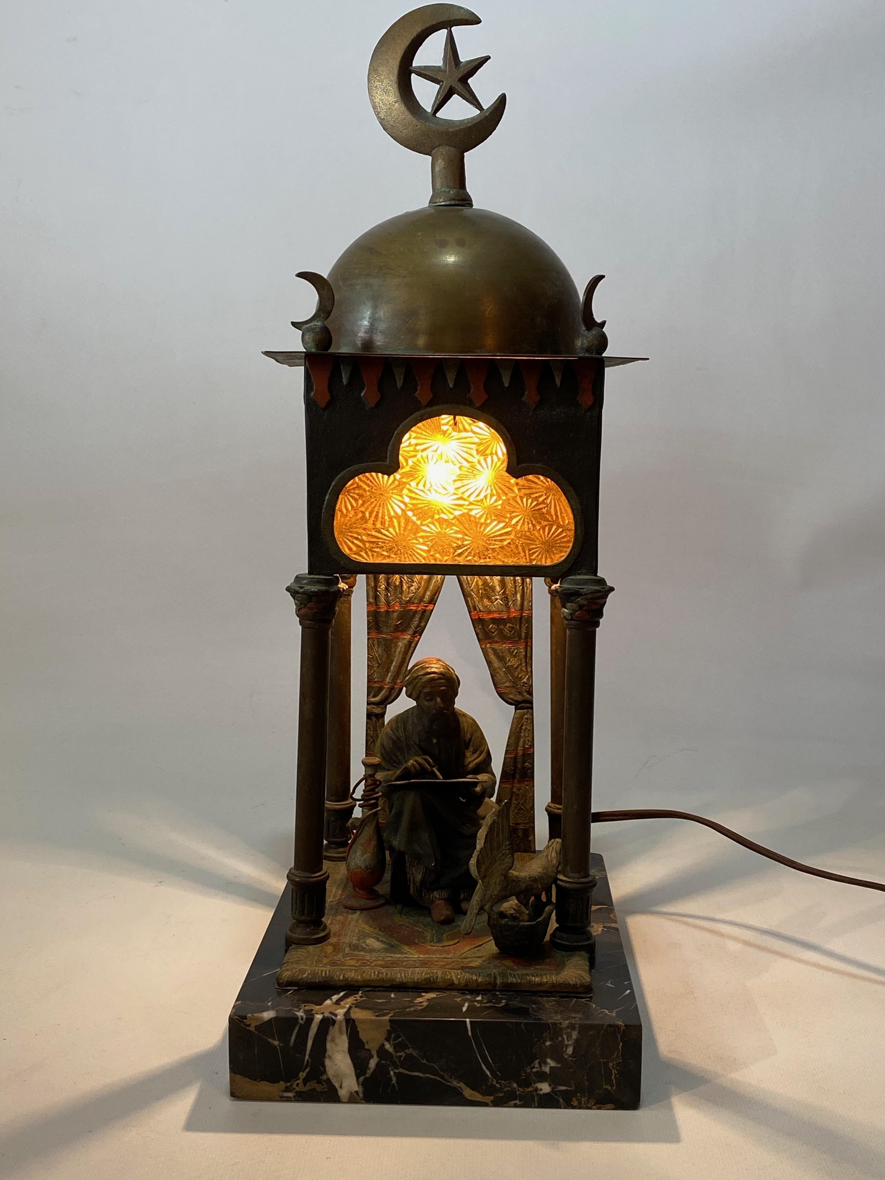 Remarkable orientalist cold painted Austrian bronze lamp featuring a Belgian black marble base, four texture glass panels, the crescent star and most importantly a seated holy man or scribe on a prayer rug. Signed, Ruff on the rear of the piece.