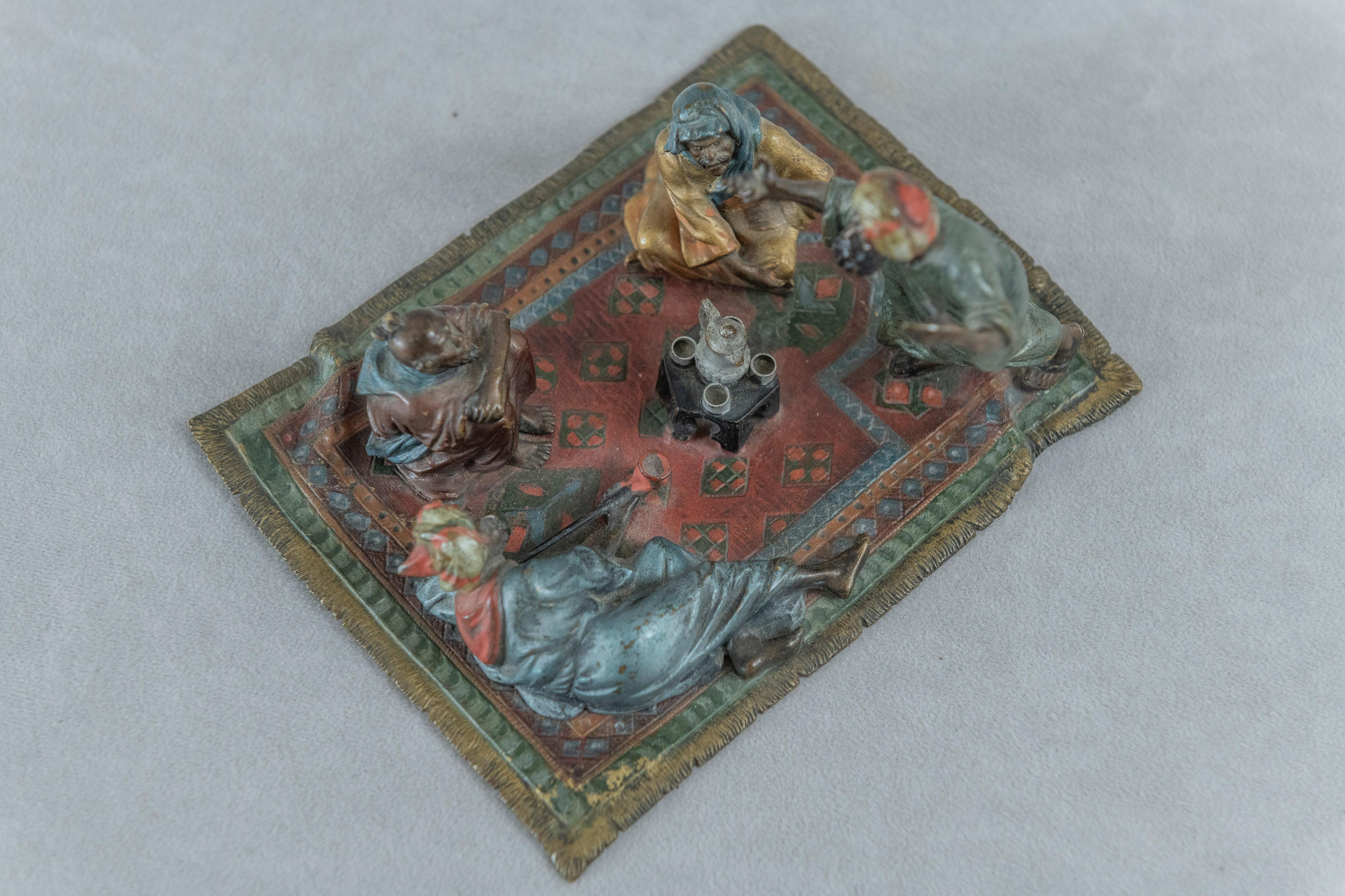 This colorfully cold painted Vienna bronze brings to the viewer a lovely little scene. The gentleman standing on a carpet is explaining something to his 3 other countrymen who are resting on the same carpet. It is charming scene with great detail