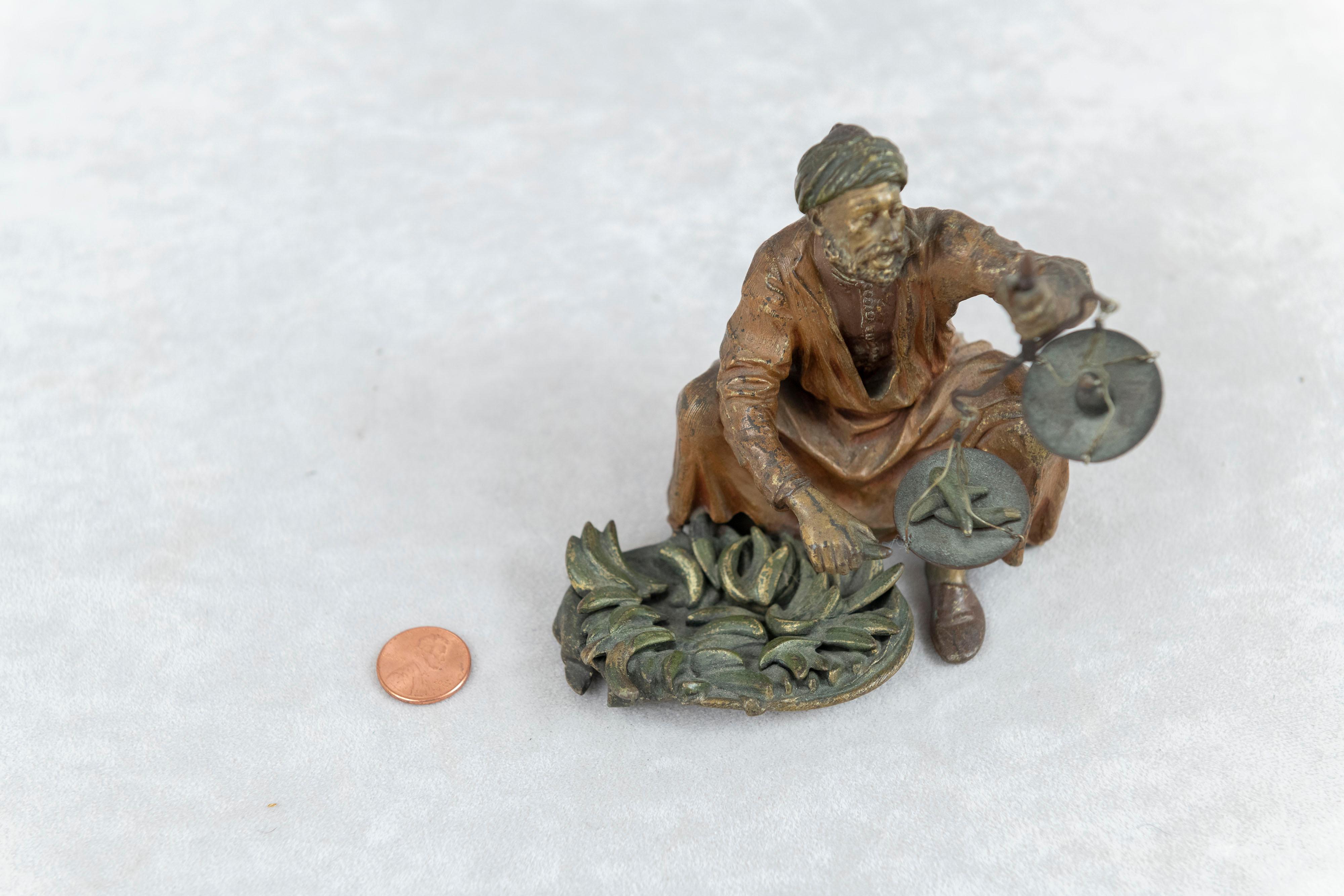  An unusual cold painted Vienna bronze of a seated man holding a little scale in his left hand. The scale has a small weight on the scale while a banana is weighing heavier on the other side. An example of Bergmann's work that we have never seen.