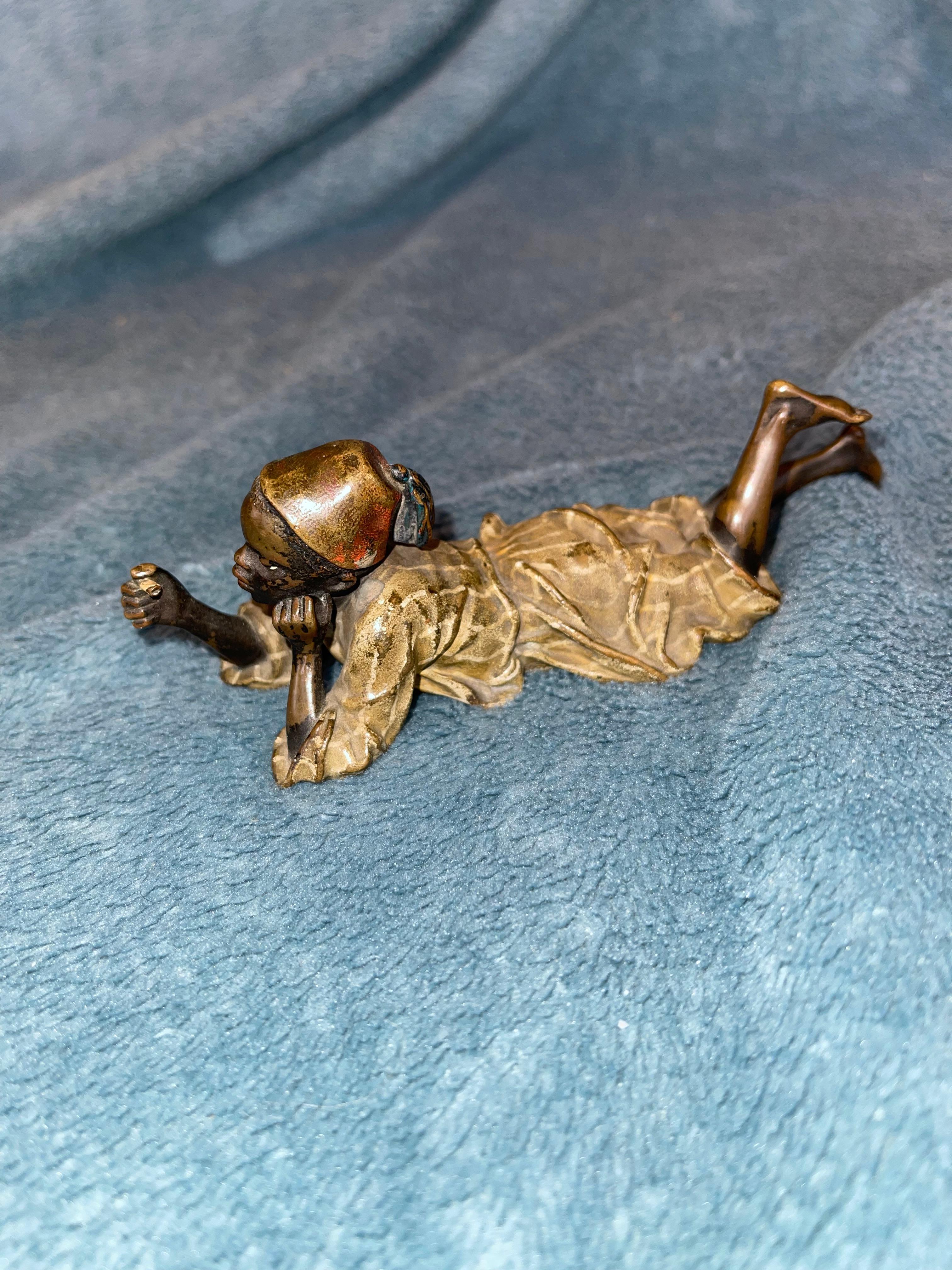  This well designed and executed Vienna bronze has a young boy resting on his stomach and enjoying what is left of a cigar. His clothes are meticulously cold painted, and this bronze is signed in multiple areas. It does bear the Bergmann Foundry