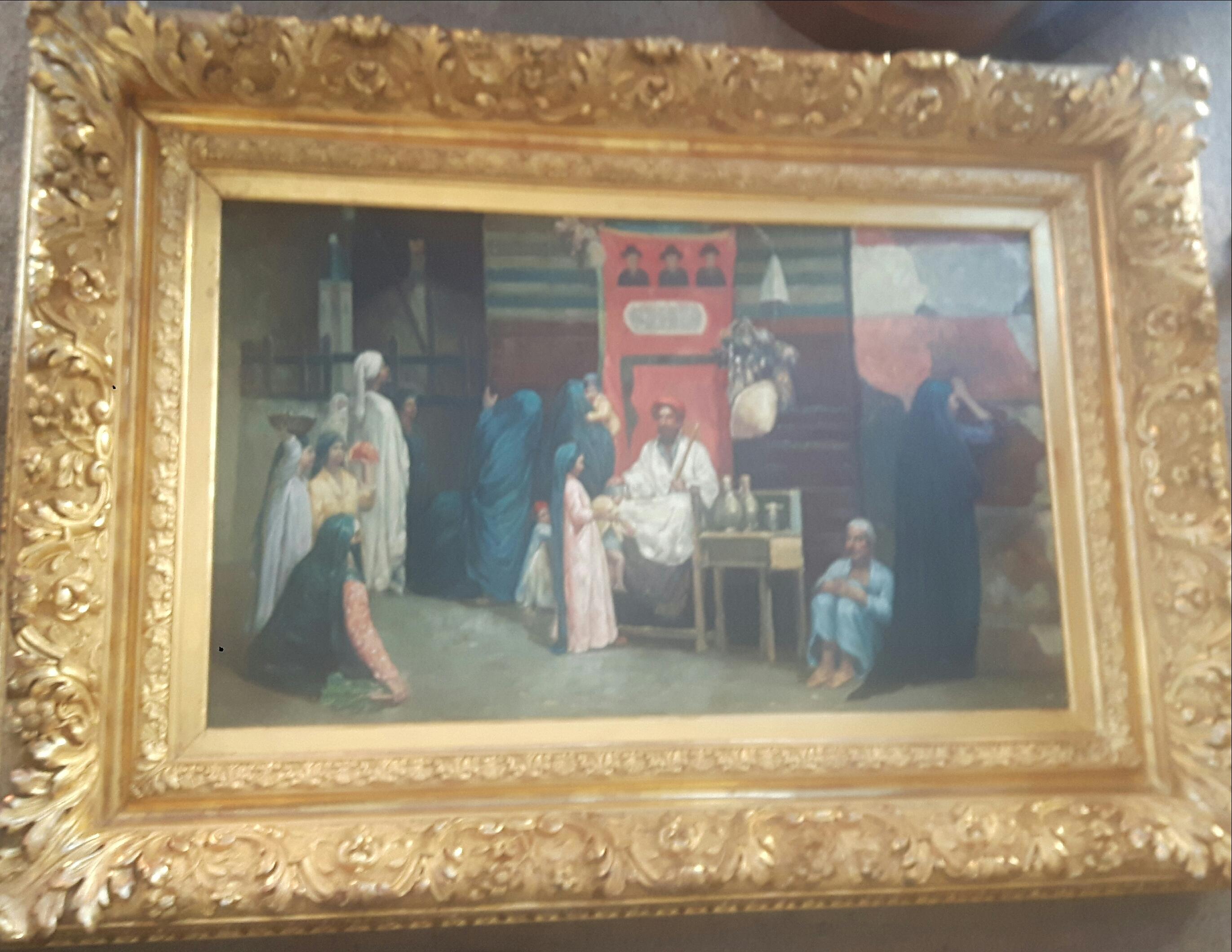 Orientalist painting of a holy man blessing a young child, whilst women and men look on, awaiting their turn, some women are bearing gifts of food and a man, probably the Imams valet, waits and look on.