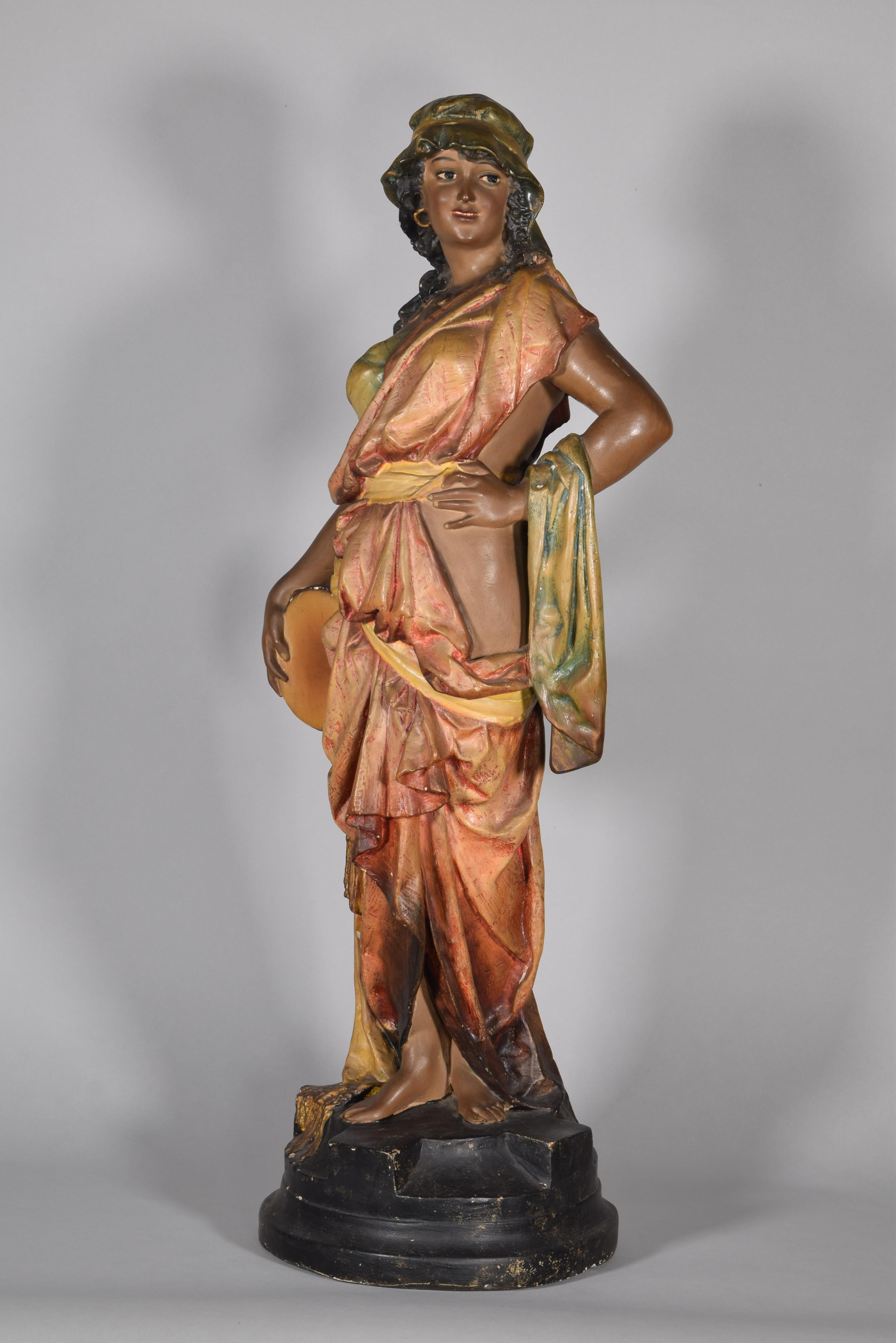 Orientalist sculpture. Polychrome plaster, 19th century.
Female figure made in polychrome plaster that shows a young woman standing on a circular base, dressed in clothing that was considered exotic at the time, with a suggestive pose and a