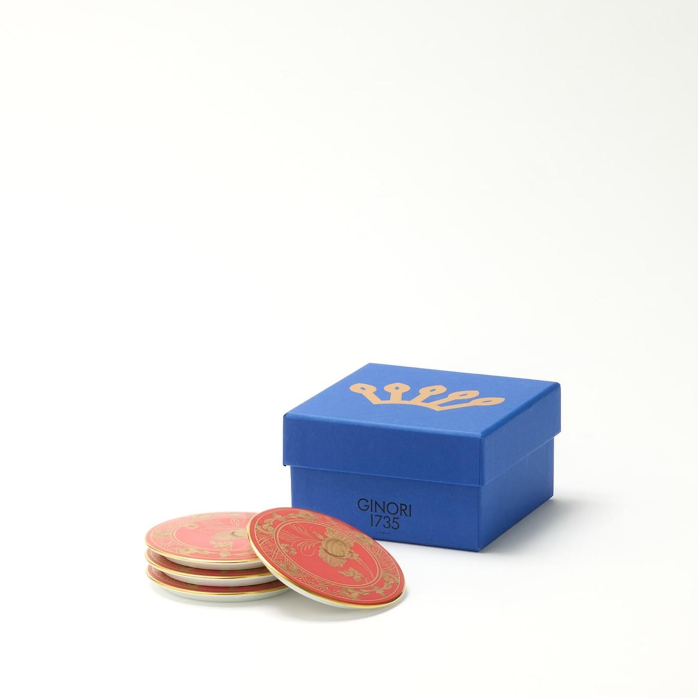 Juego de 4 posavasos decorativos Rubrum de la colección Oriente Italiano. Estos cuatro posavasos de porcelana roja, con intrincados motivos florales. El ribete dorado realza la belleza del motivo Rubrum, infundiendo vitalidad y alegría a cualquier